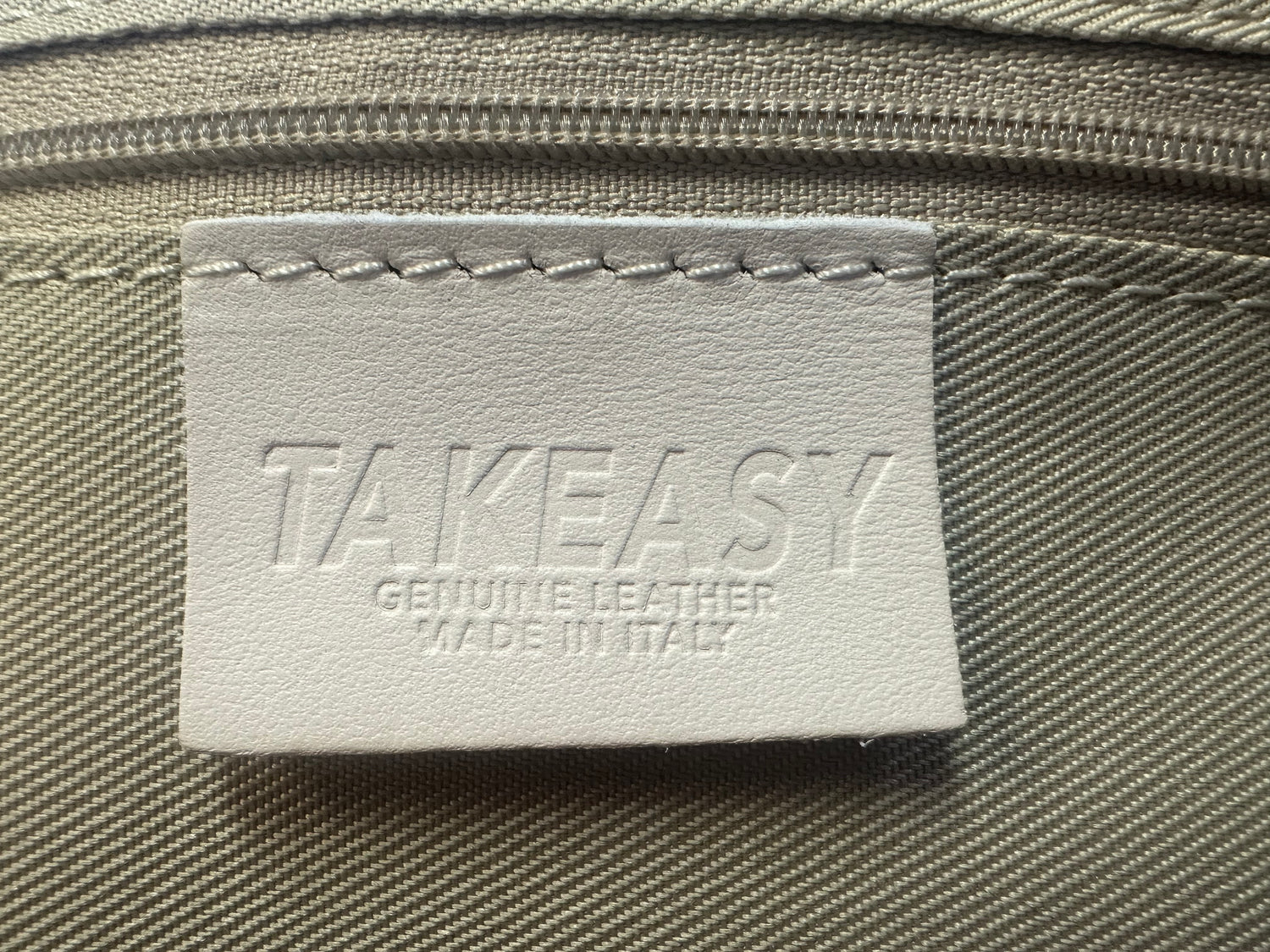 Close-up of 'Genuine Leather – Made in Italy' label sewn inside handbag