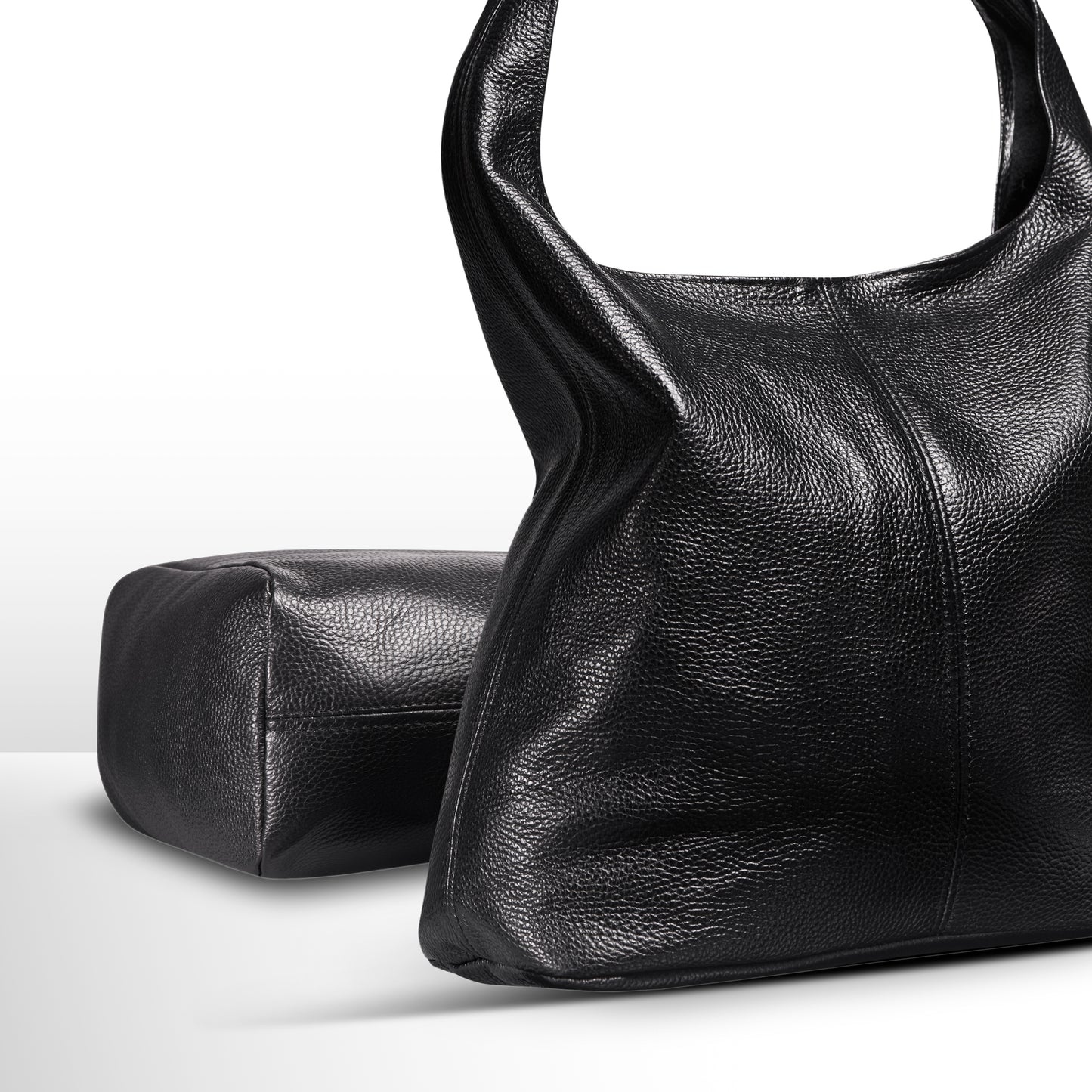 Black textured leather handbag with a structured design and a rectangular pouch beside it.