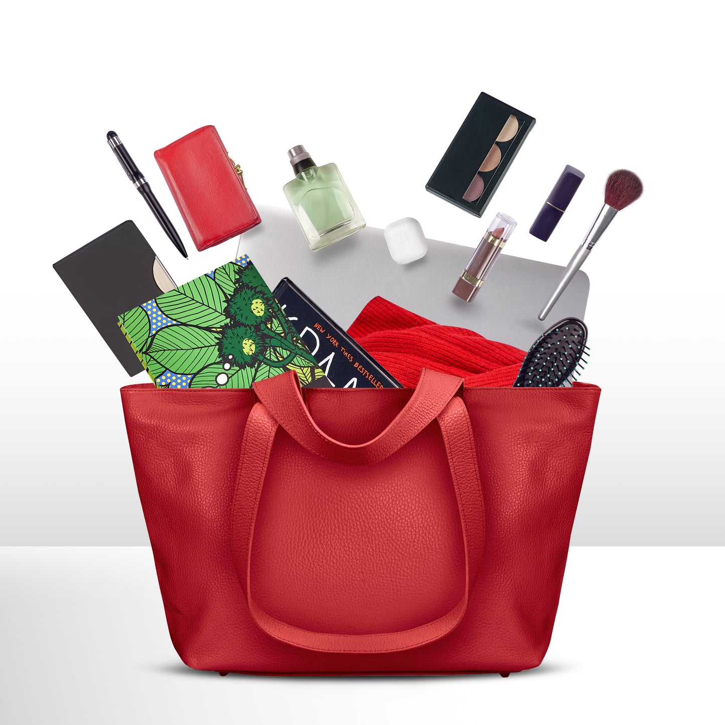 A red Italian leather bag with various items spilling out, including a notebook, printed fabric, wallet, pen, perfume, sunglasses, AirPods, lipstick, makeup palette, brush set, hairbrush, and a matching red scarf.