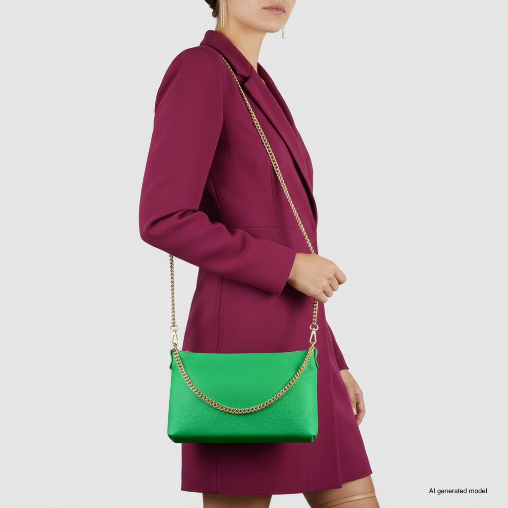 A person in a magenta blazer dress holds a small structured handbag with a gold chain strap over their shoulder. The bright green accessory stands out against the plain white background.