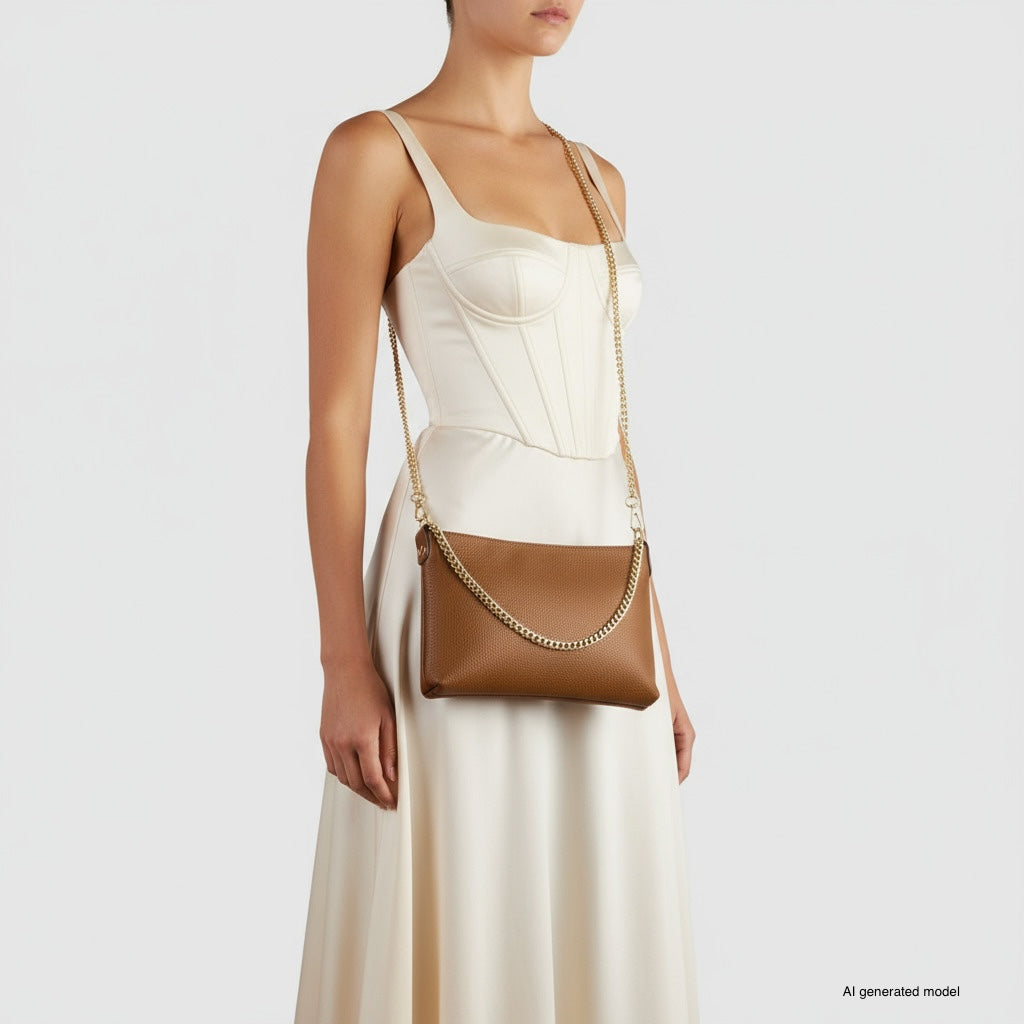 A woman in a sleeveless, ivory dress holds a small structured handbag with a gold chain strap. She stands against a plain white background, her head partially out of frame.