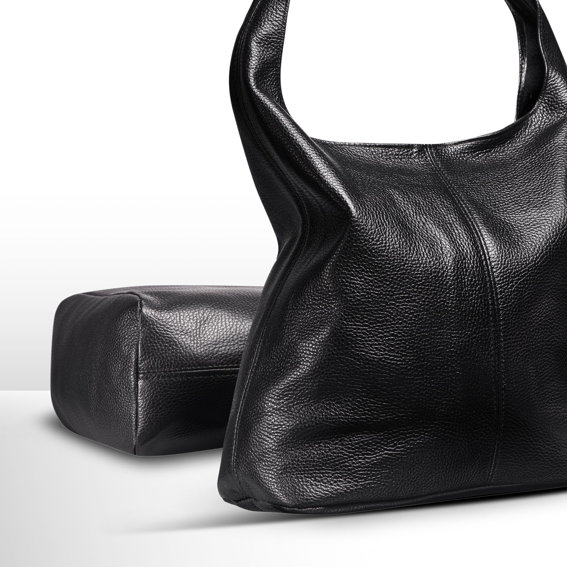 Black textured leather handbag with a structured design and a rectangular pouch beside it.