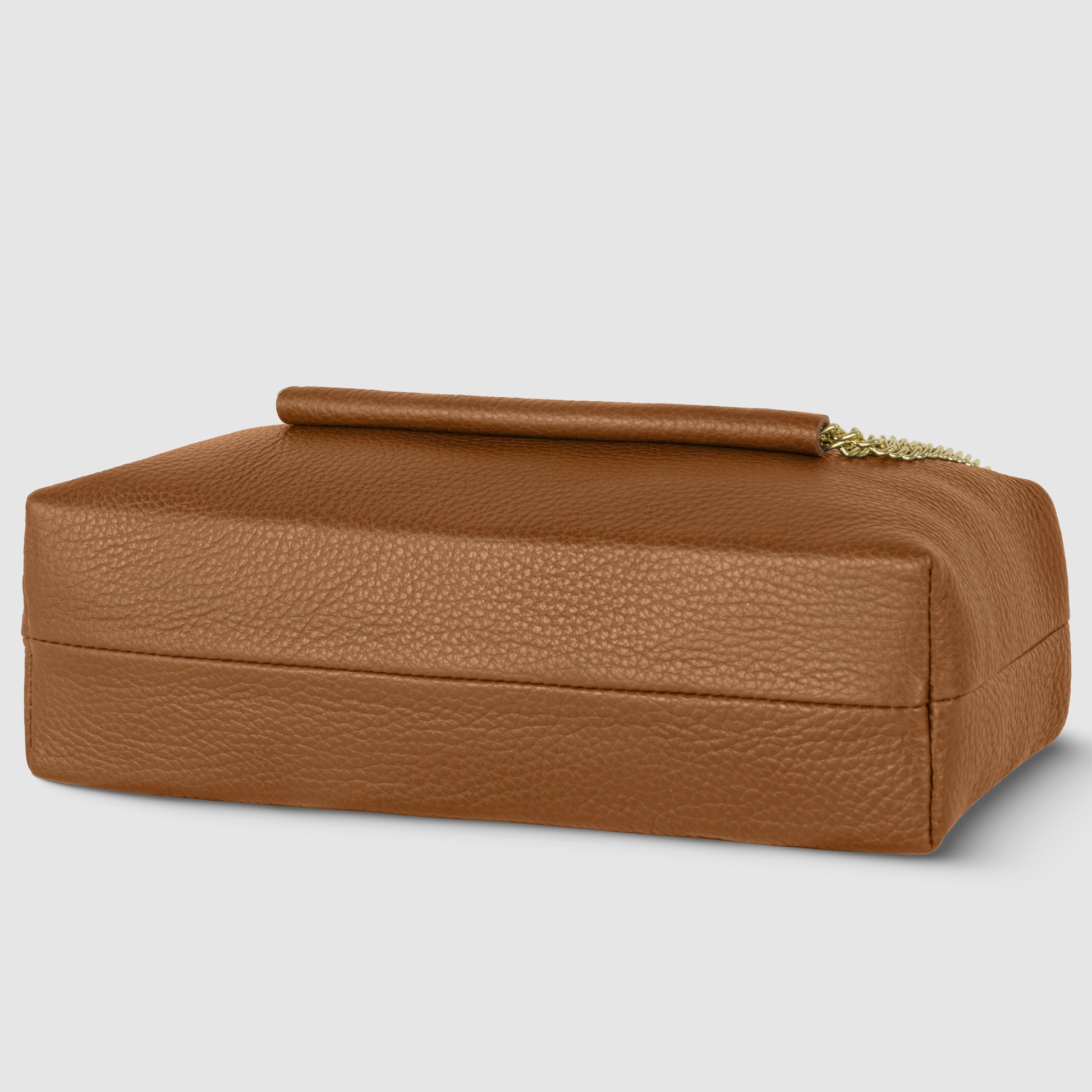 A rectangular brown Italian leather bag with a handle and gold chain detail sits on a light gray background. Text reads Handcrafted in Italy with a small Italian flag above it.