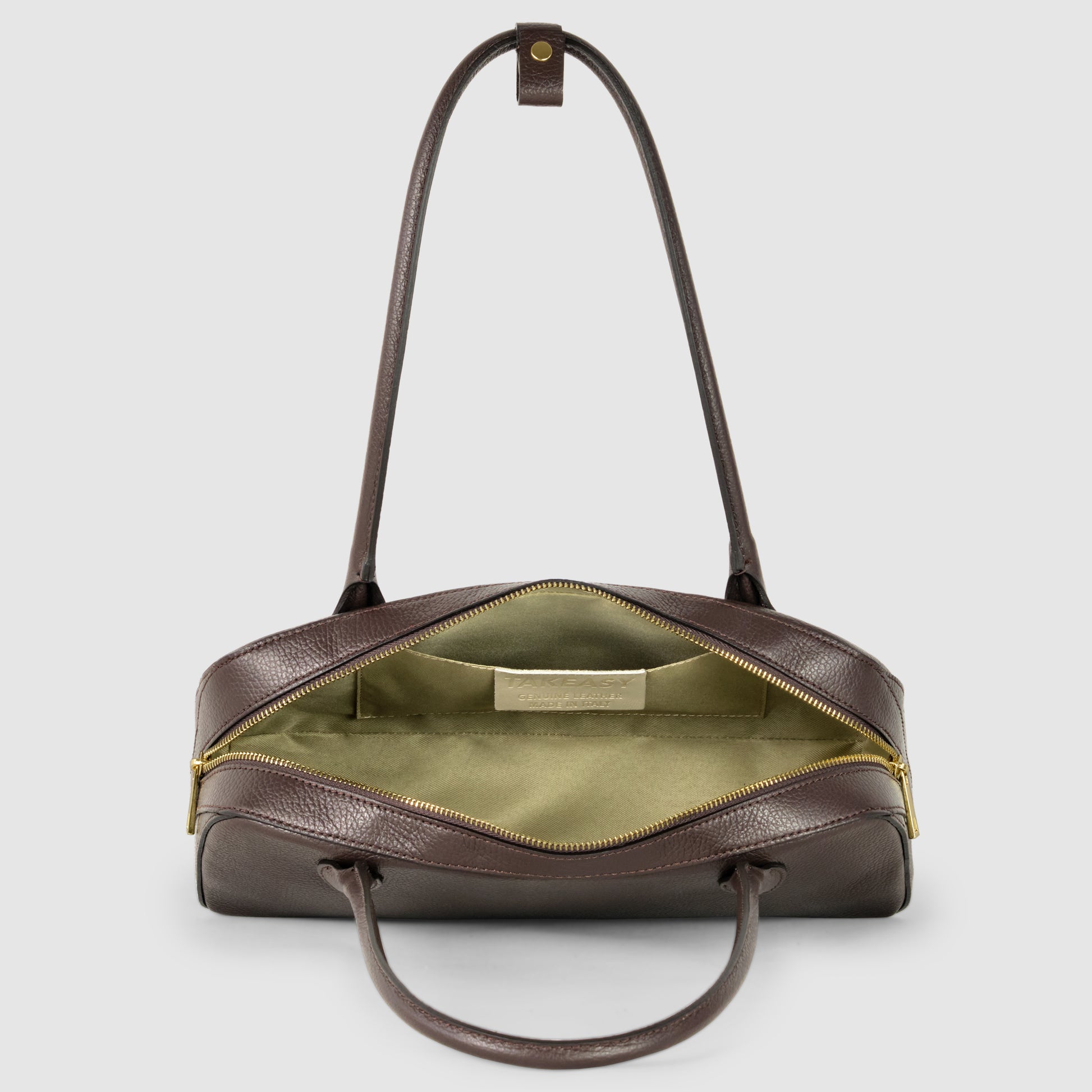 A brown Italian leather bag with gold zipper, shown from above with the zipper open to reveal a light green fabric interior and double handles, against a plain light gray background.