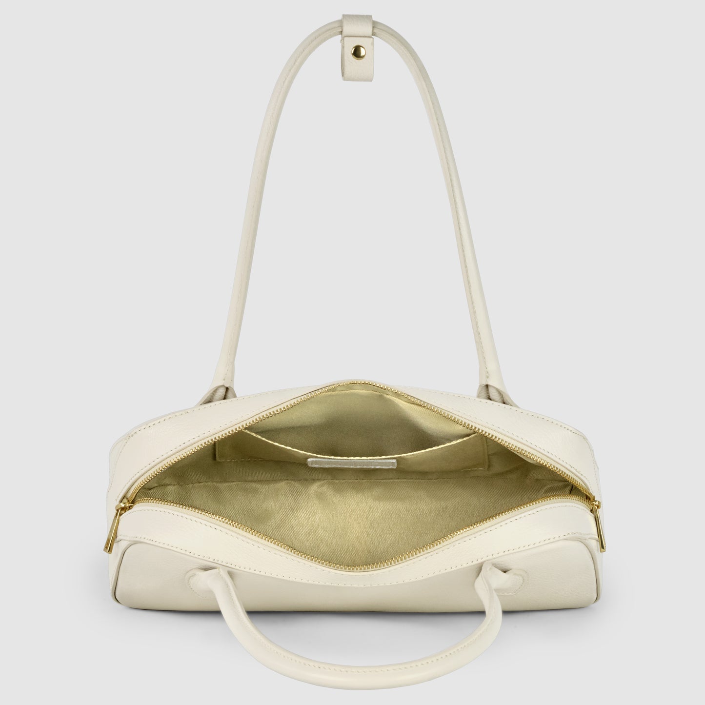 A cream-colored Italian leather bag with gold zippers is shown open, revealing a spacious, beige interior with a zippered pocket inside. The bag has two handles and highlights exquisite Florentine craftsmanship against a plain white background.