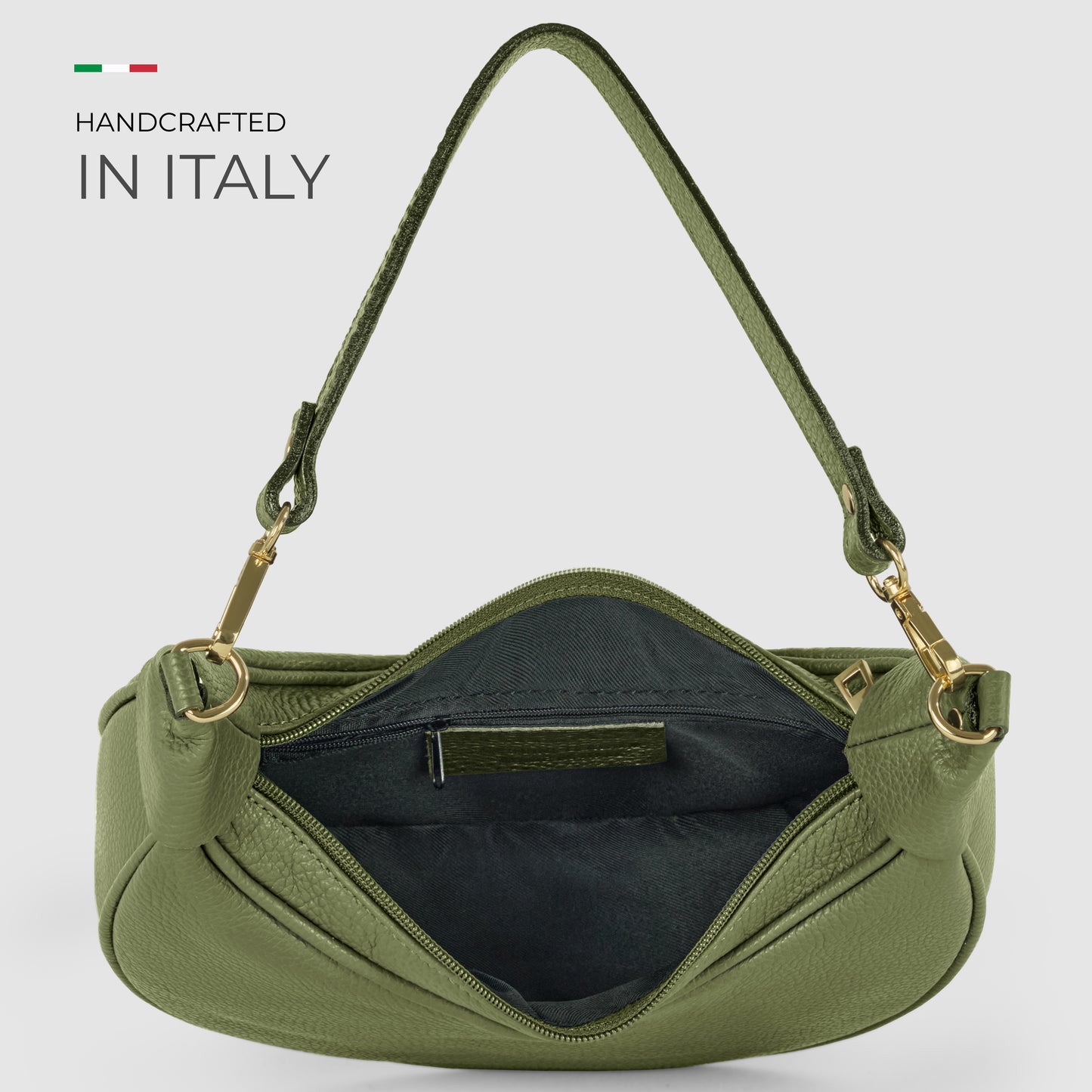 Olive green crescent-shaped handbag in Italian calf leather with gold hardware and a single handle, shown open to reveal a black fabric interior. Text reads “Handcrafted in Italy” with a small Italian flag above, reflecting artisan craftsmanship.