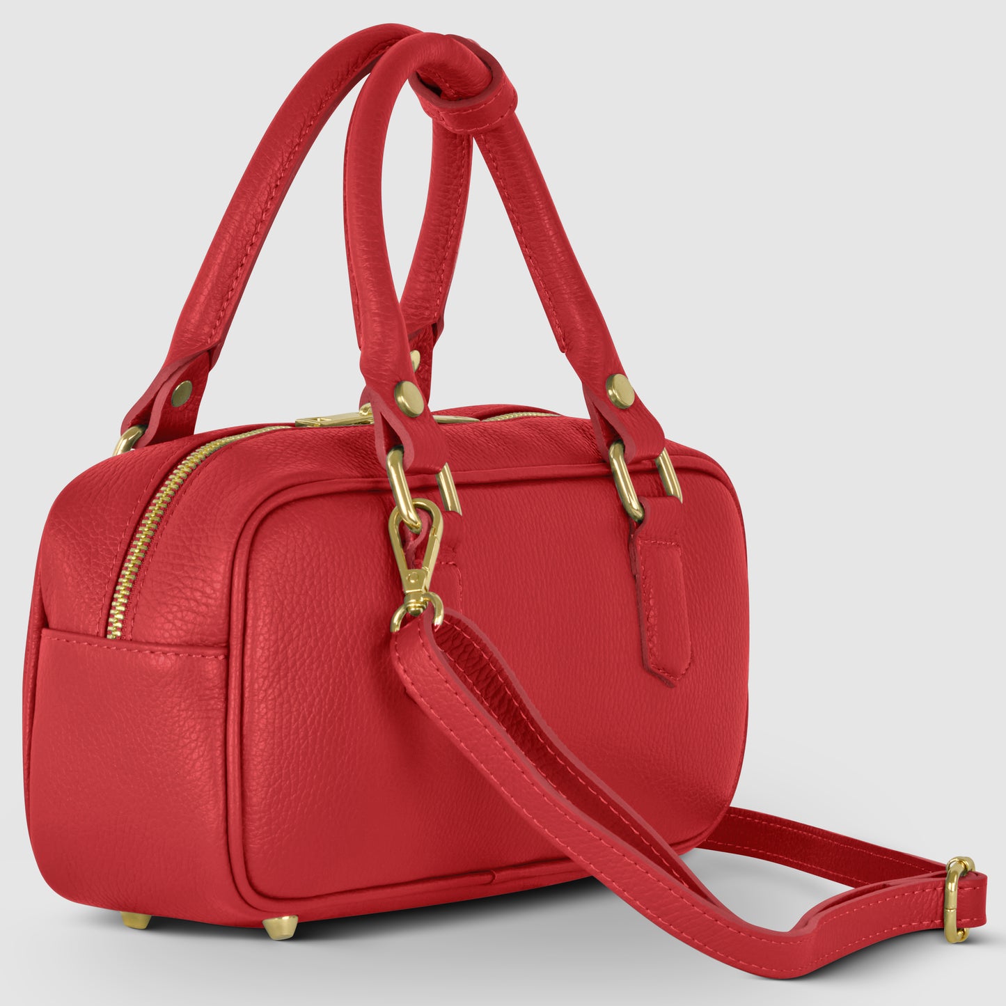 A small rectangular red Italian leather handbag with gold hardware, double handles, a detachable shoulder strap, and a zippered top, set against a plain light grey background.
