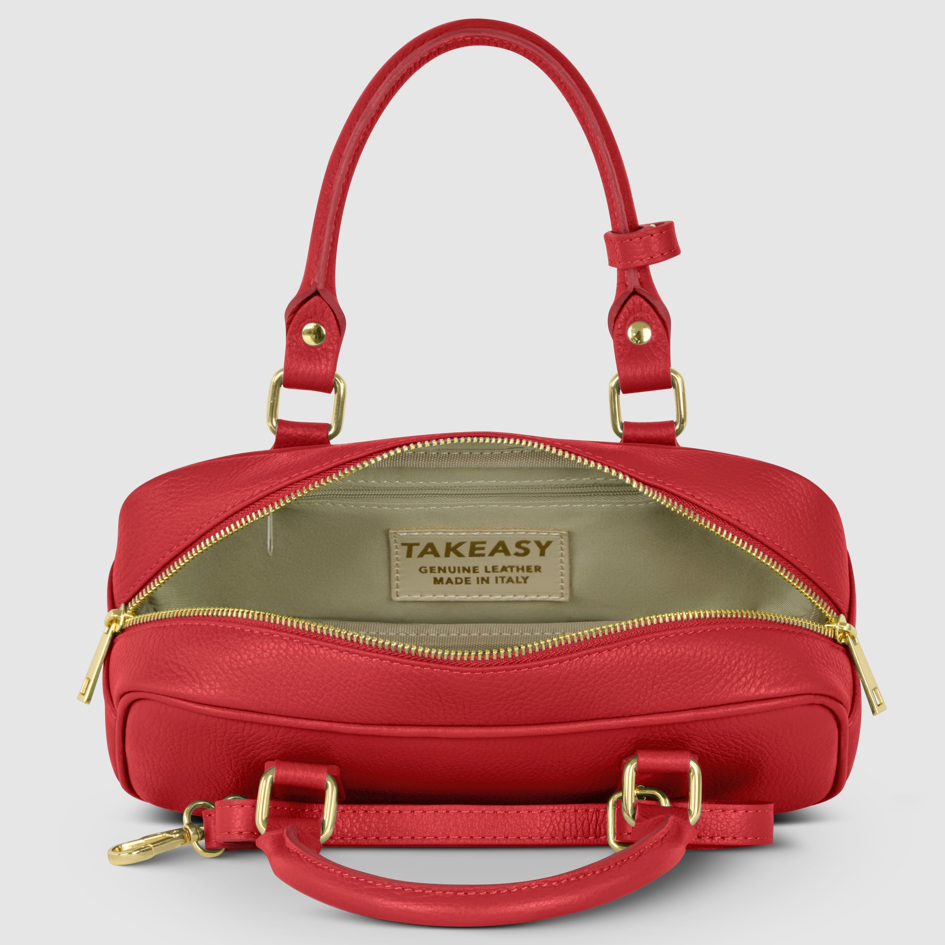 A minimalist Italian leather handbag in red is shown open, featuring gold hardware, a beige interior, and a TAKEASY Genuine Leather Made in Italy label. The background is plain and light gray.