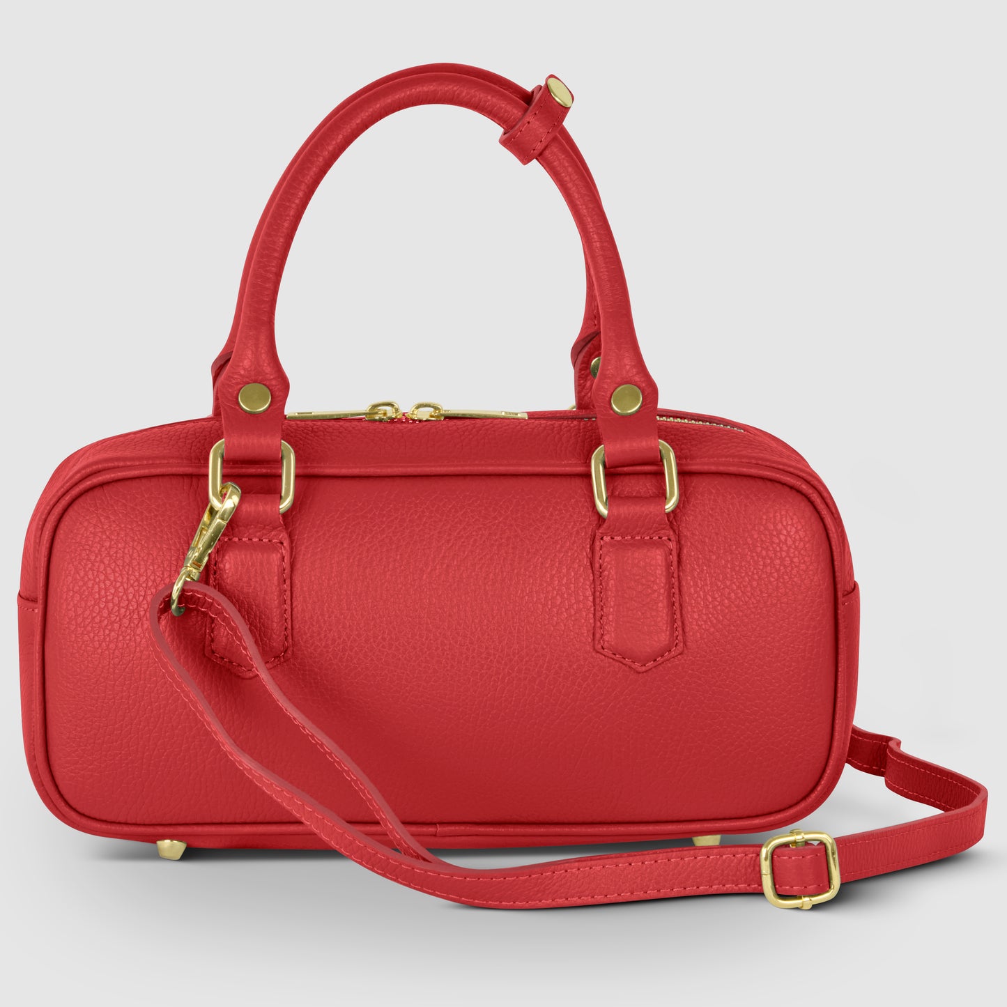 A small, rectangular Italian leather handbag in red with gold hardware, two handles, and an adjustable shoulder strap, displayed against a light gray background.