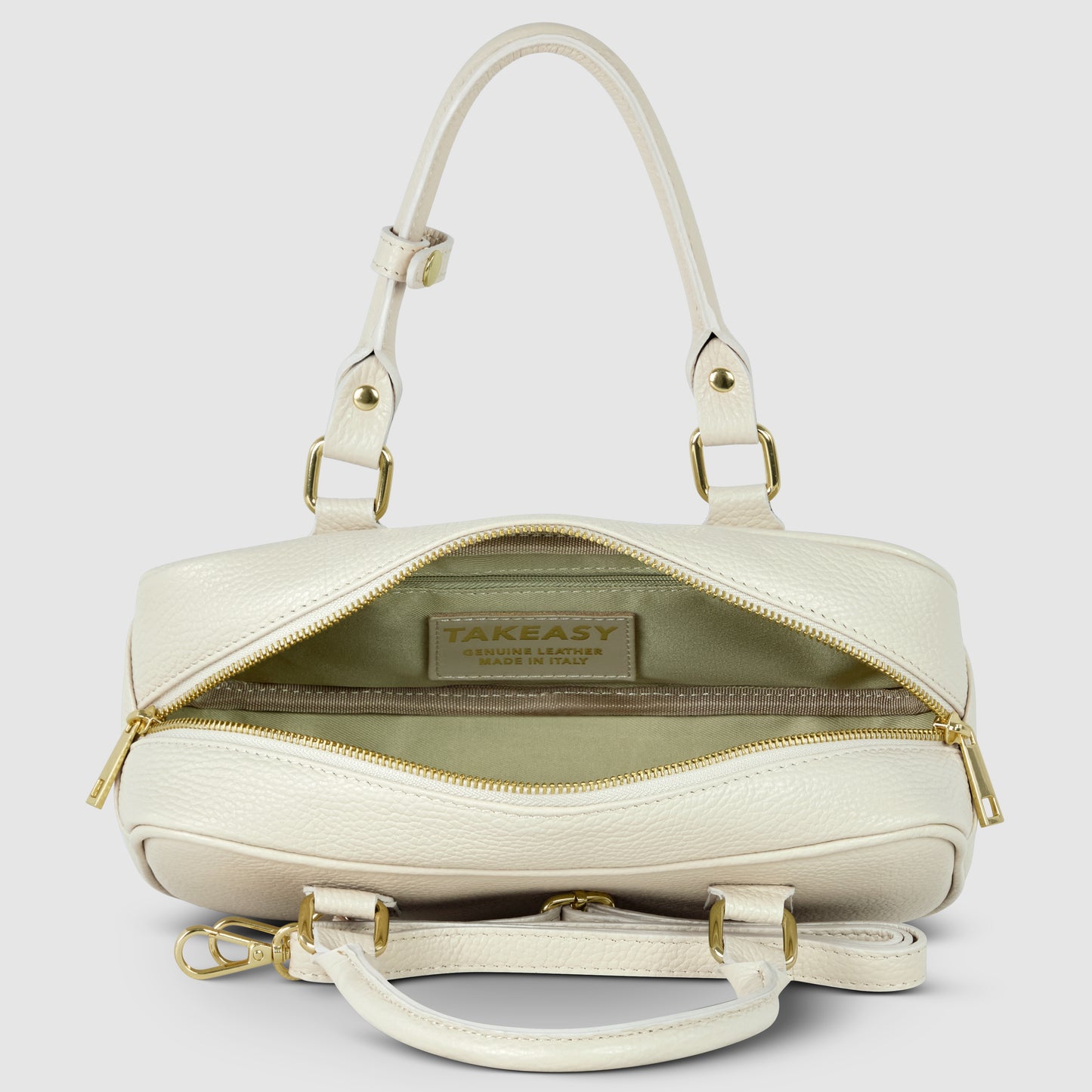 A cream-colored minimalist handbag crafted from pebbled leather, featuring gold hardware, two handles, a detachable shoulder strap, and an open zipper revealing a beige interior with a visible TAKEASY brand label.