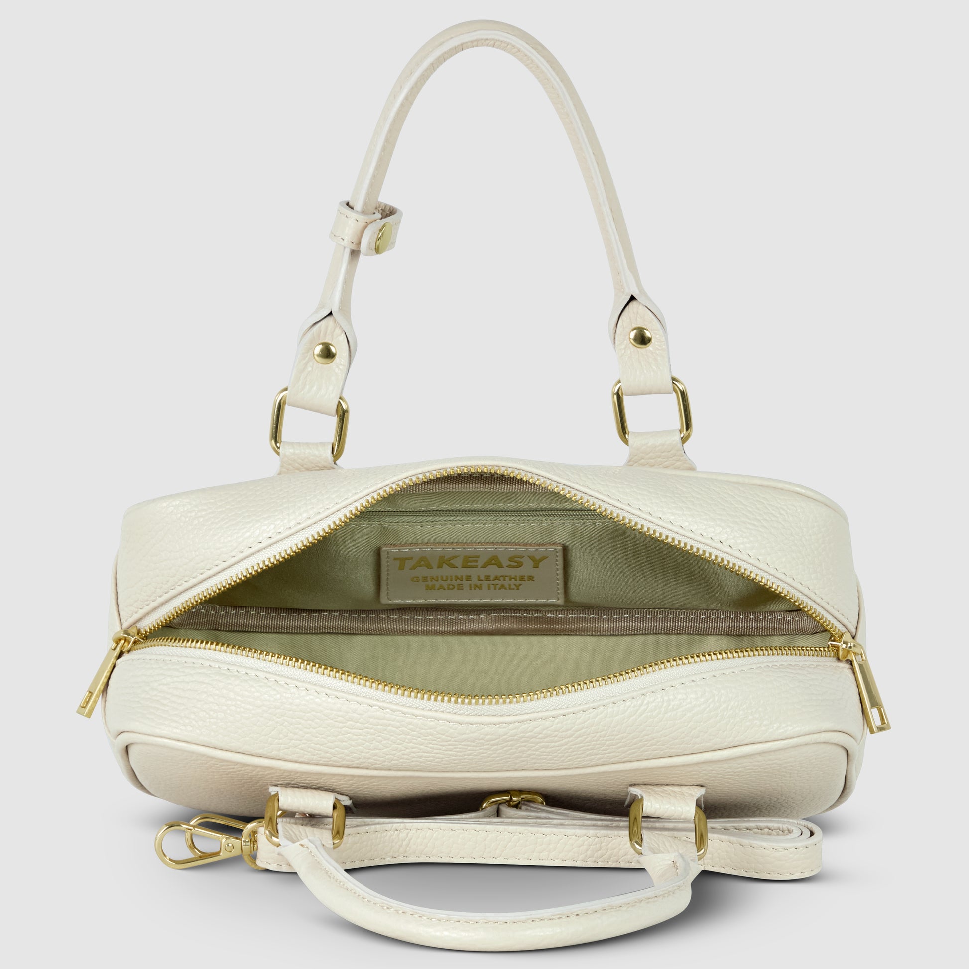 A cream-colored minimalist handbag crafted from pebbled leather, featuring gold hardware, two handles, a detachable shoulder strap, and an open zipper revealing a beige interior with a visible TAKEASY brand label.