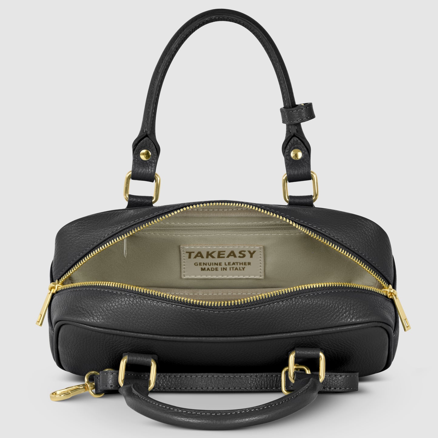 A minimalist Italian leather handbag with gold hardware is shown open, revealing a beige interior and a TAKEASY GENUINE LEATHER MADE IN ITALY label. The bag has two handles and a zippered closure.