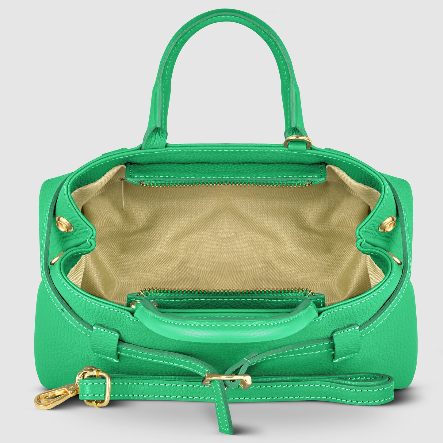A green Italian leather handbag with gold hardware is open to show its beige interior, inner zip pocket, and matching green handles and detachable strap with a buckle, all beautifully handmade in Italy.