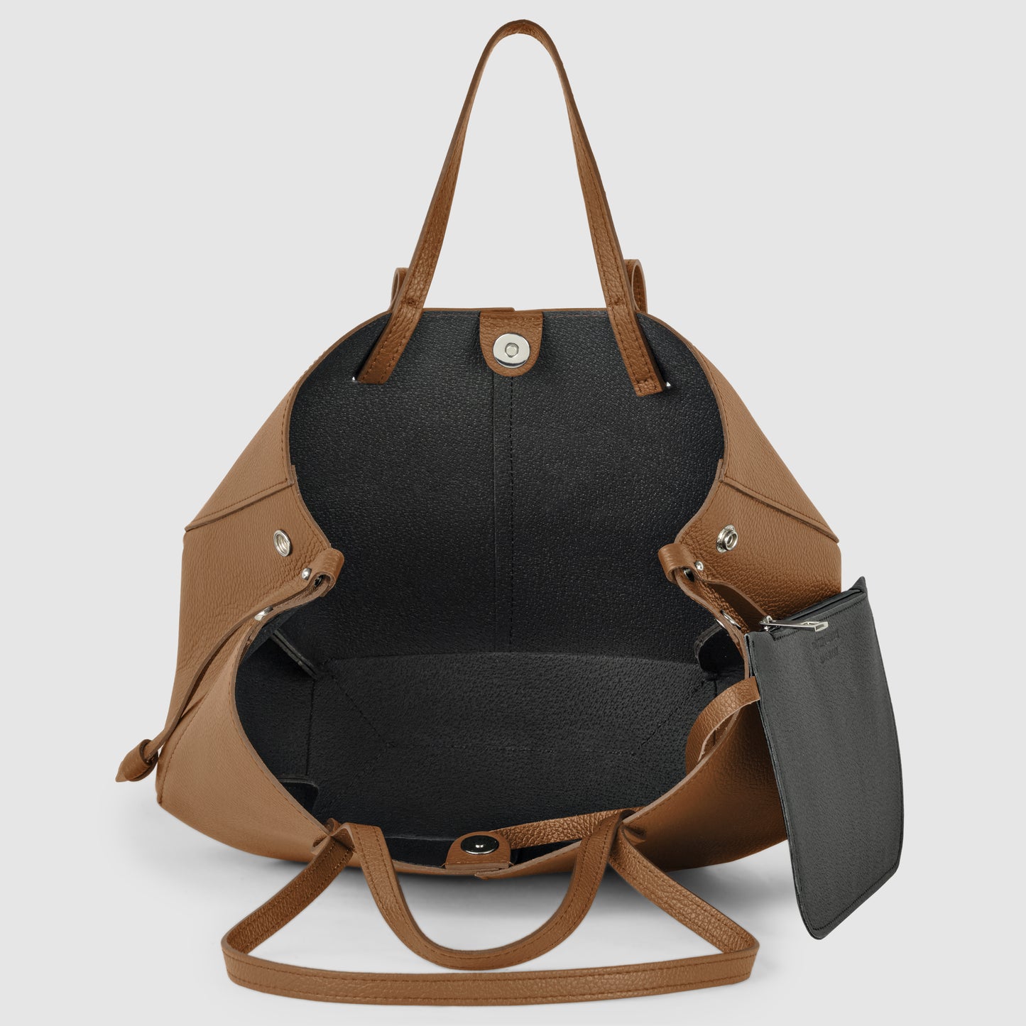 Brown Italian leather handbag with two handles, open to reveal a spacious black interior and a detachable black zip pouch. This handcrafted in Italy convertible tote stands empty and upright against a plain background.