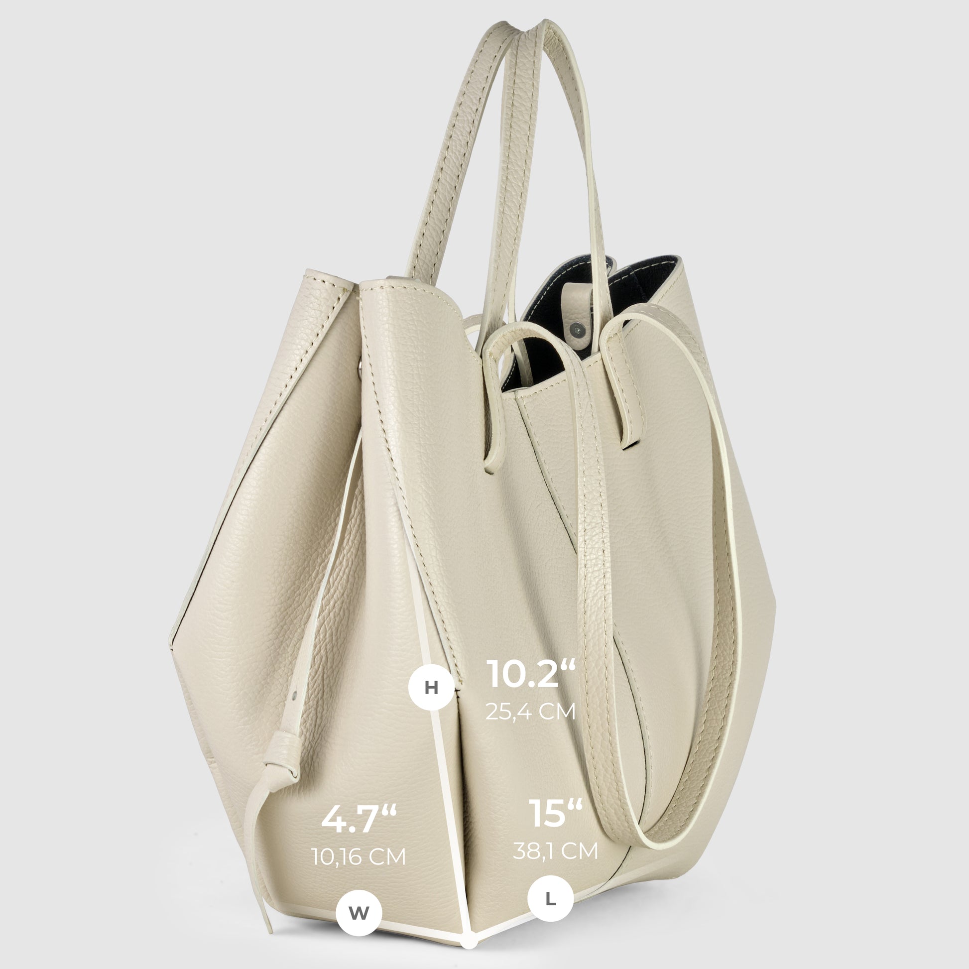 A light beige Italian leather handbag tote with two handles stands upright, showcasing its dimensions: Height 10.2 inches (25.4 cm), Width 4.7 inches (10.16 cm), Length 15 inches (38.1 cm).