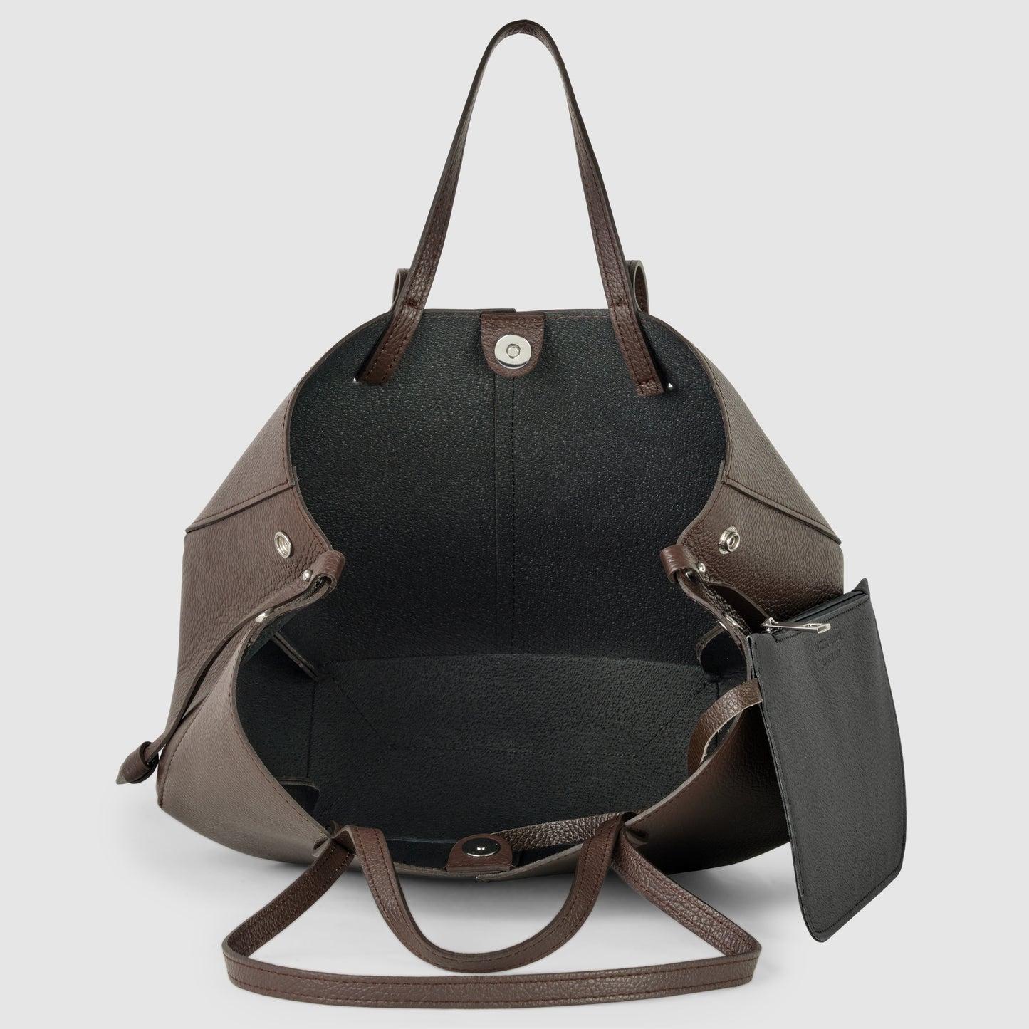 A large brown Italian leather handbag with an open top reveals a spacious interior and a small black zip pouch attached inside. Handcrafted in Italy, this tote has two handles and is displayed against a plain light background.
