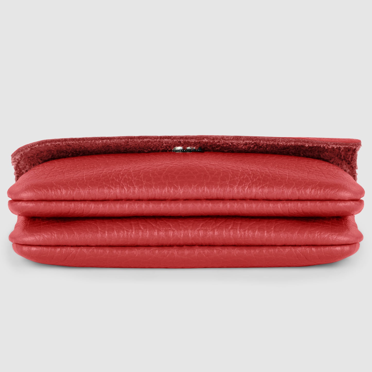 A red handmade calf leather wallet lies flat and closed on a light gray background, with the textured flap slightly raised, revealing part of a silver clasp.
