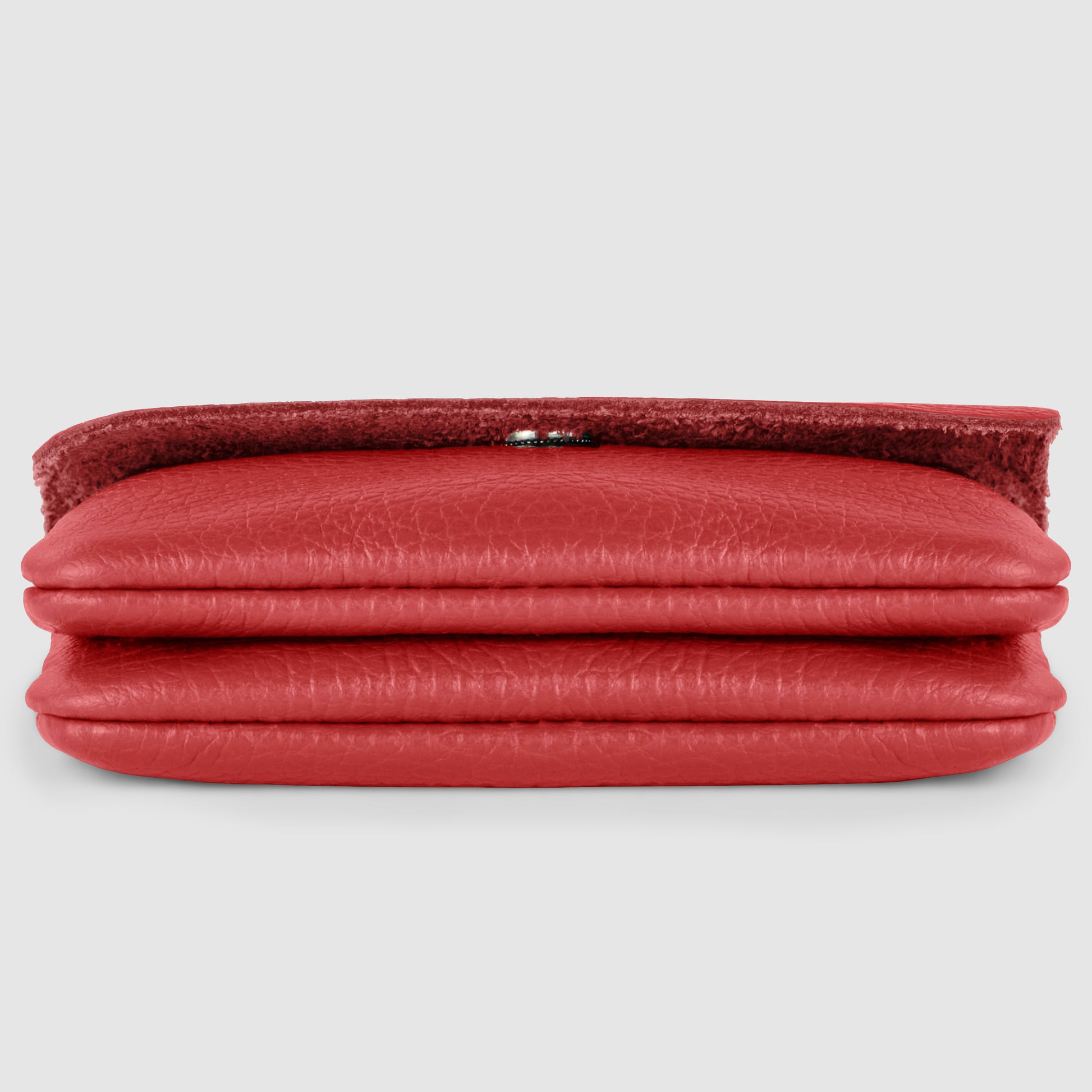 A red handmade calf leather wallet lies flat and closed on a light gray background, with the textured flap slightly raised, revealing part of a silver clasp.