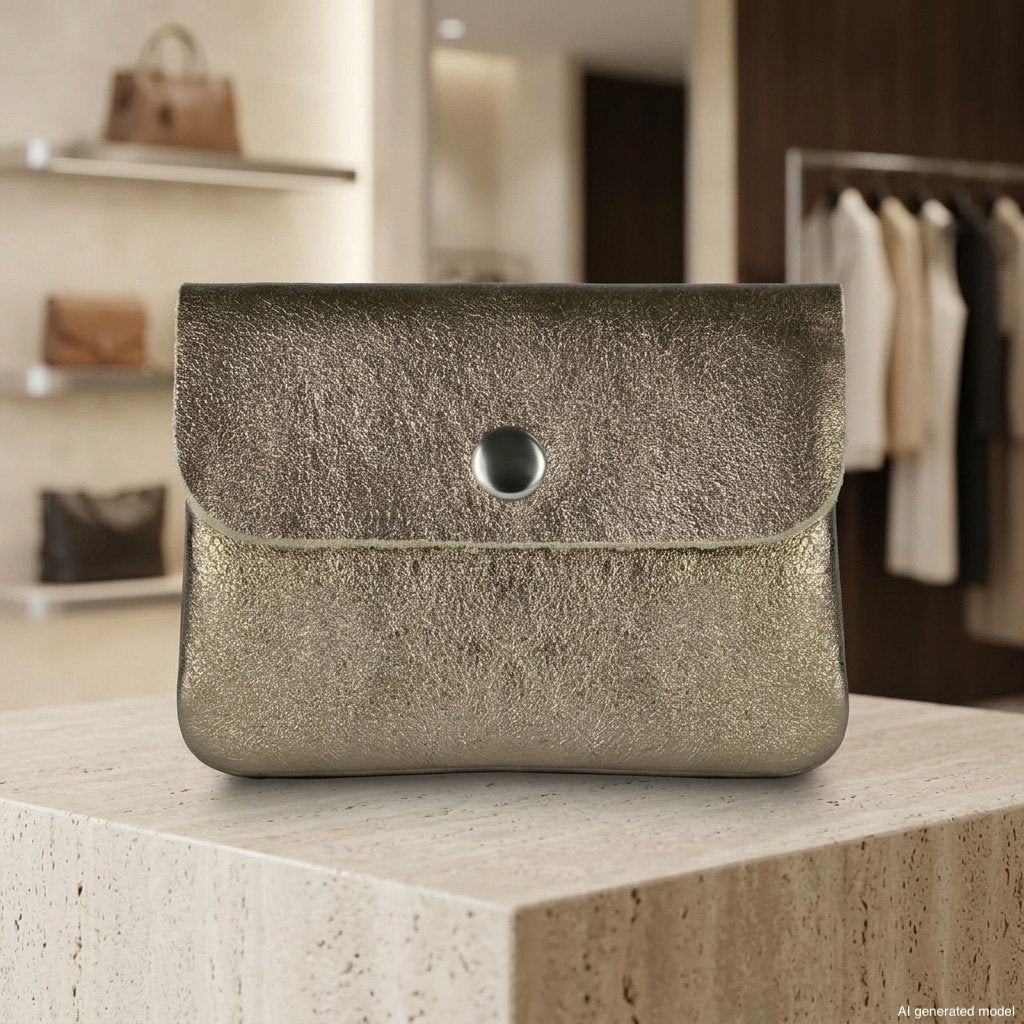 A metallic gold clutch purse, reminiscent of an Italian handmade wallet with its exquisite detailing, sits on a stone display in a modern boutique with shelves and hanging clothes in the background.