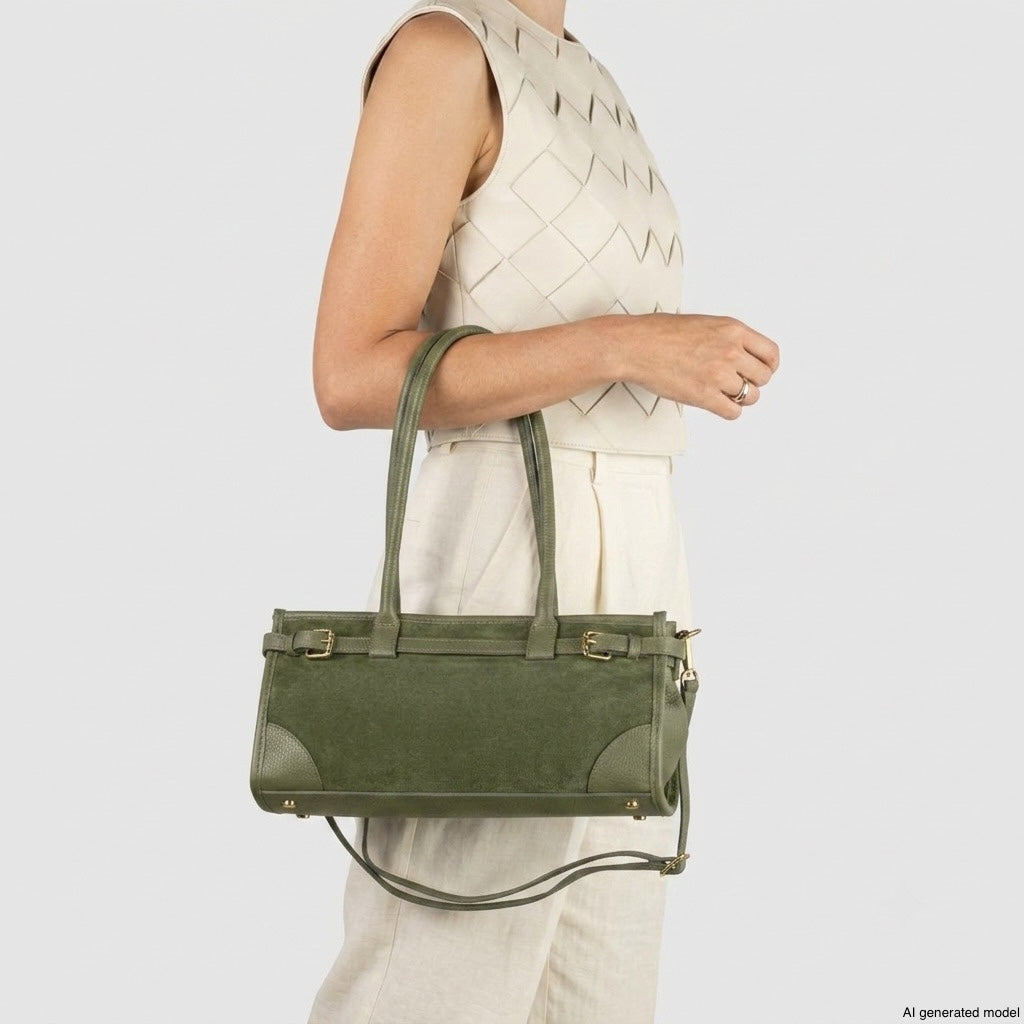 A person wearing a sleeveless, light-colored outfit holds a structured handbag with double handles and gold hardware, crafted from Italian leather, against a plain background.