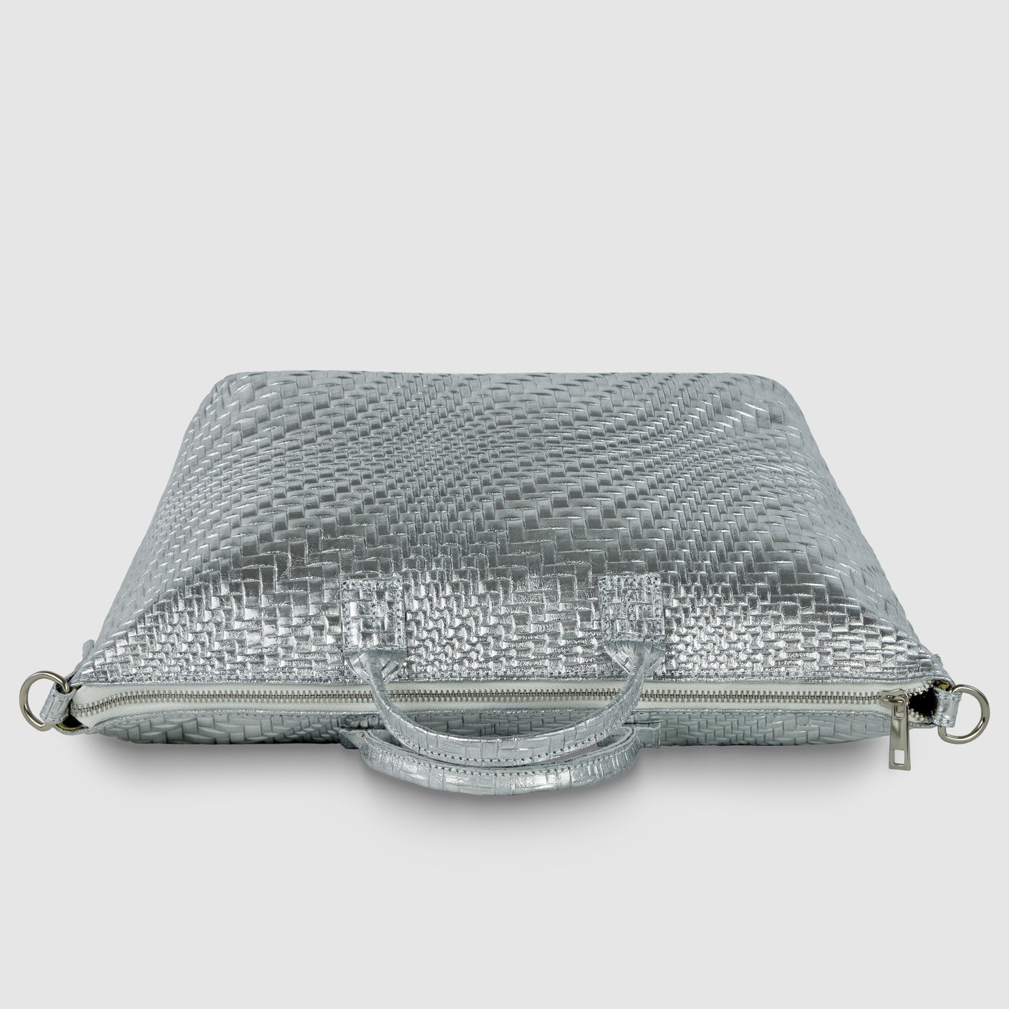 A silver, textured, rectangular grid-embossed purse with a woven pattern, handles, zipper closure, and metal rings on the sides, displayed against a plain white background.
