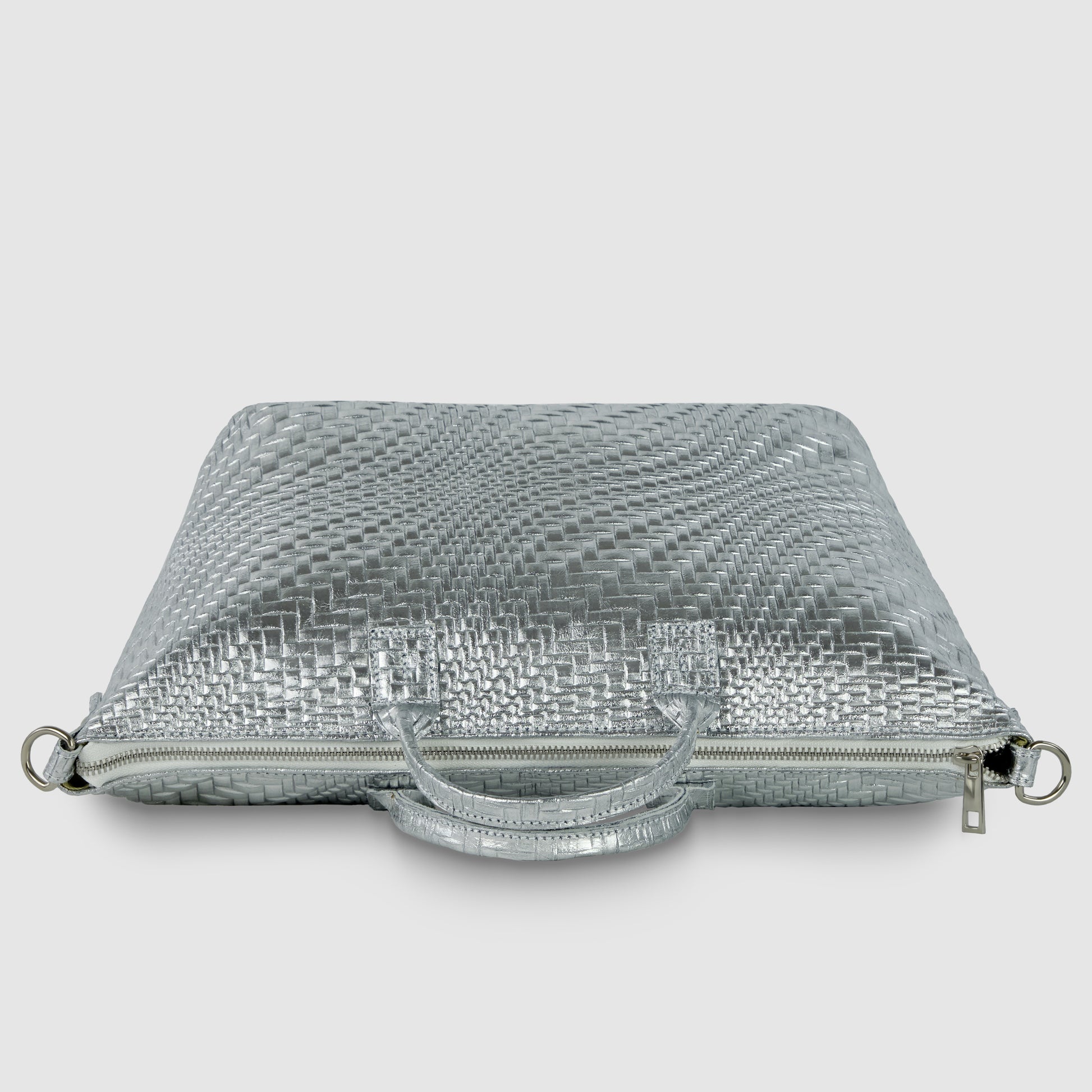 A silver, textured, rectangular grid-embossed purse with a woven pattern, handles, zipper closure, and metal rings on the sides, displayed against a plain white background.