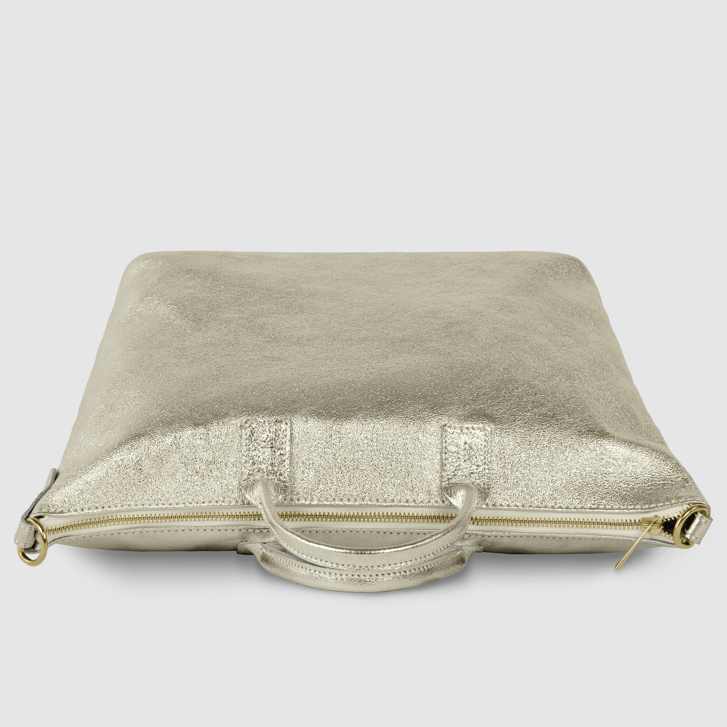 A metallic gold, square-shaped Italian handbag with a zipper and two handles, lying flat on a light gray surface.