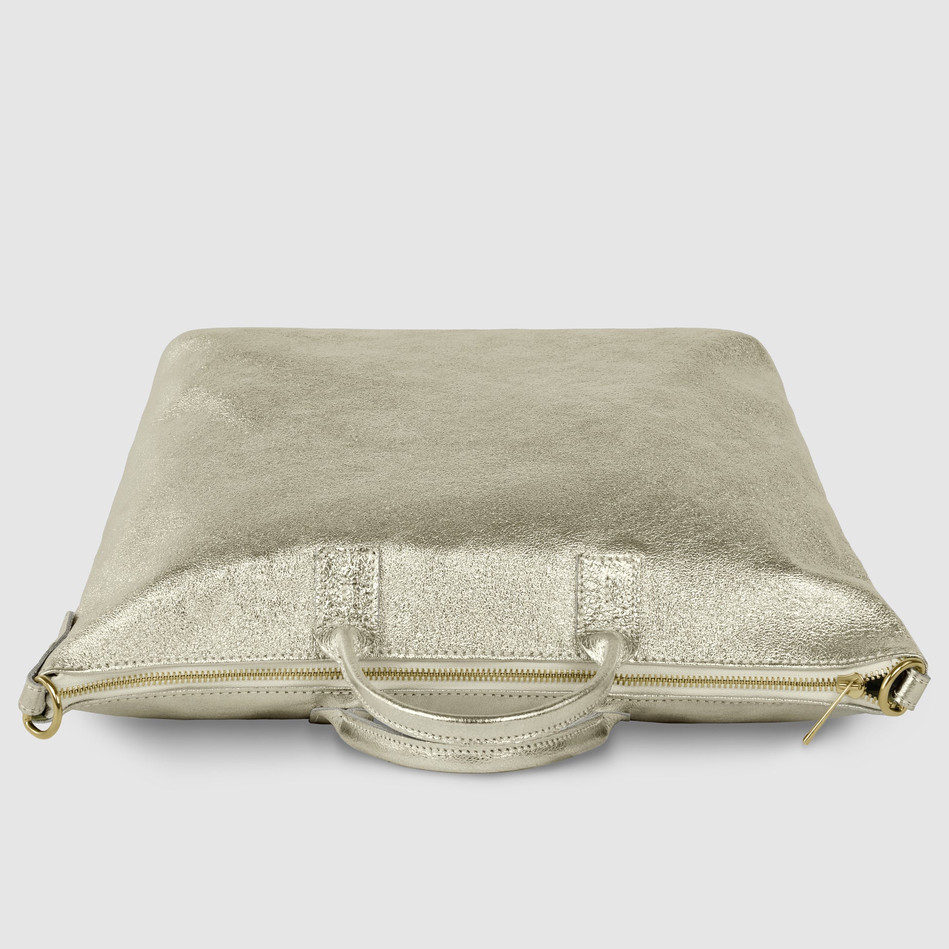 A metallic gold, square-shaped Italian handbag with a zipper and two handles, lying flat on a light gray surface.