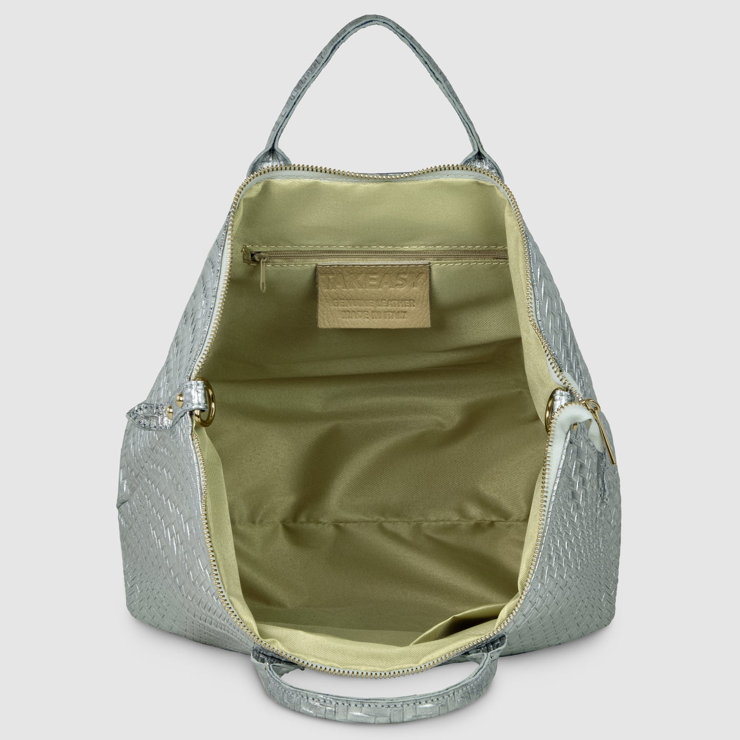 A silver textured women's handbag with its zipper open, revealing a spacious beige interior, a small zippered pocket, and a visible beige brand label inside.