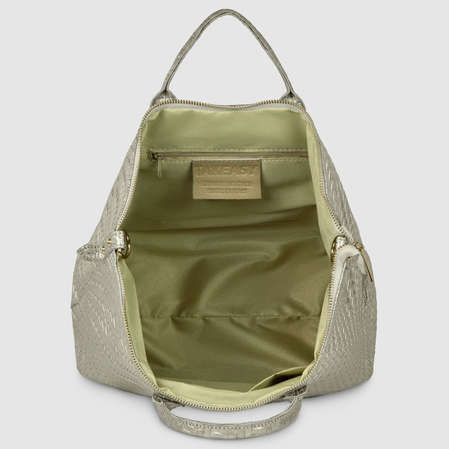 A light beige, textured handcrafted designer bag stands open, revealing its spacious, pale green interior with a zippered pocket and a visible rectangular label stitched on the inside.