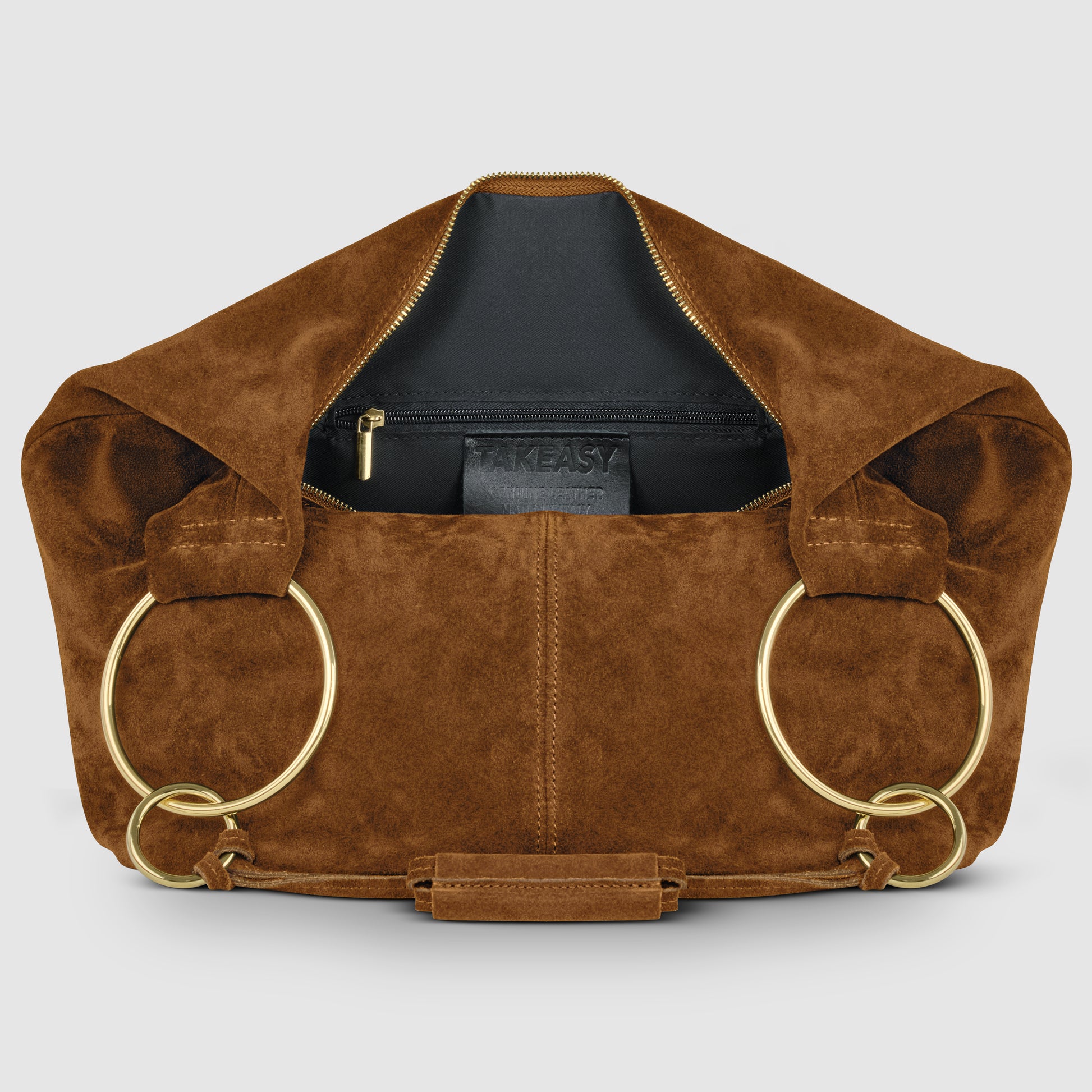 A brown natural suede handbag with large gold rings as handles is open to reveal a black interior, zippered pocket, and a visible "TAKEASY" label inside.