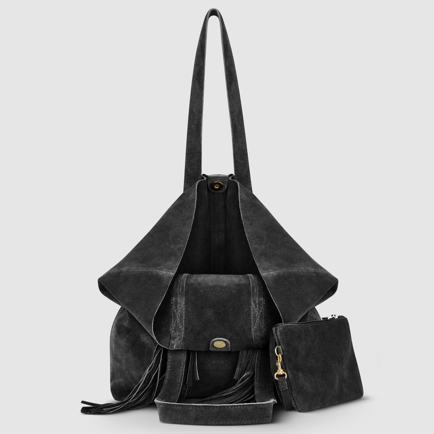 A black suede handbag with long handles, an open flap revealing the interior, a front pocket with a clasp, decorative tassels, and a matching small zippered pouch beside it—all set against a plain light gray background.
