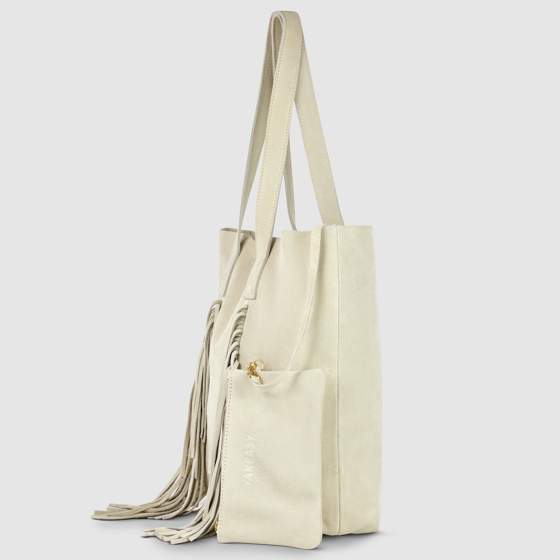 A light beige suede handbag with long handles, decorative side tassels, and a matching zippered pouch attached to the handle. This bohemian handbag features subtle MAKARSKA gold lettering on the pouch.
