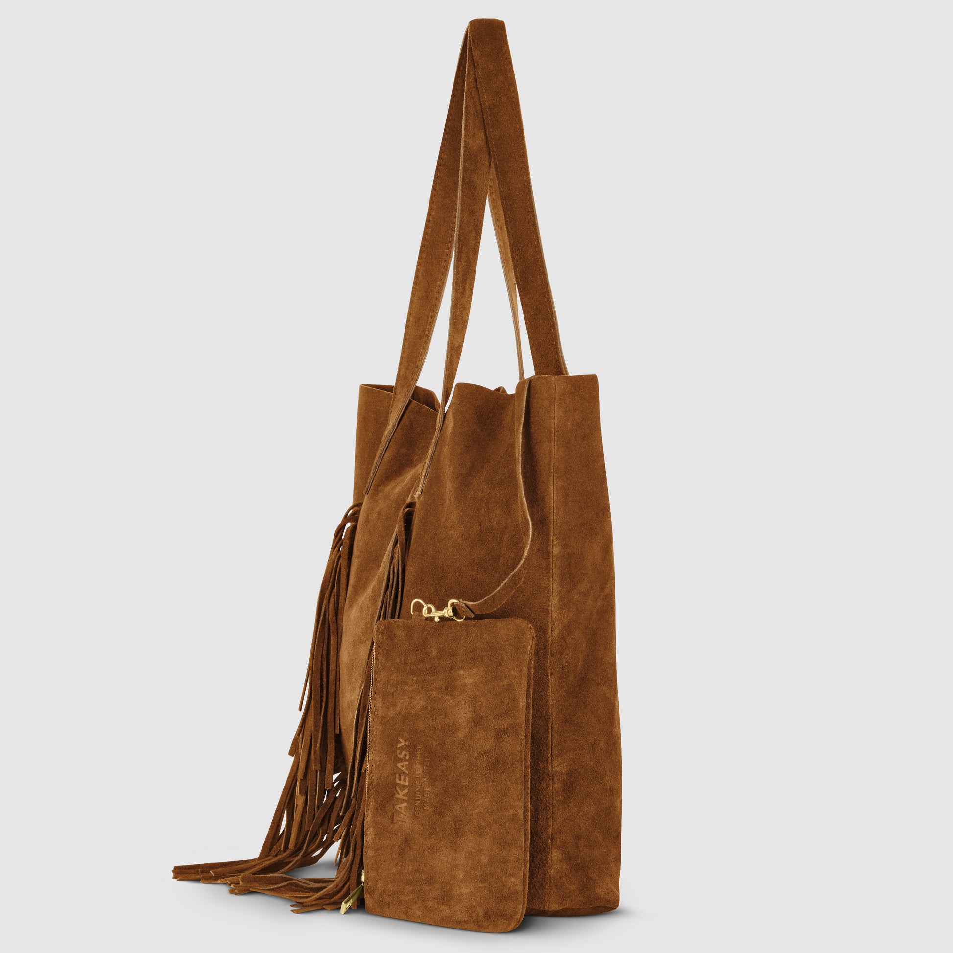 A brown suede handbag with long handles, fringe detailing on the side, and an attached matching zippered pouch. This boho bag features a soft, textured finish for effortless style.