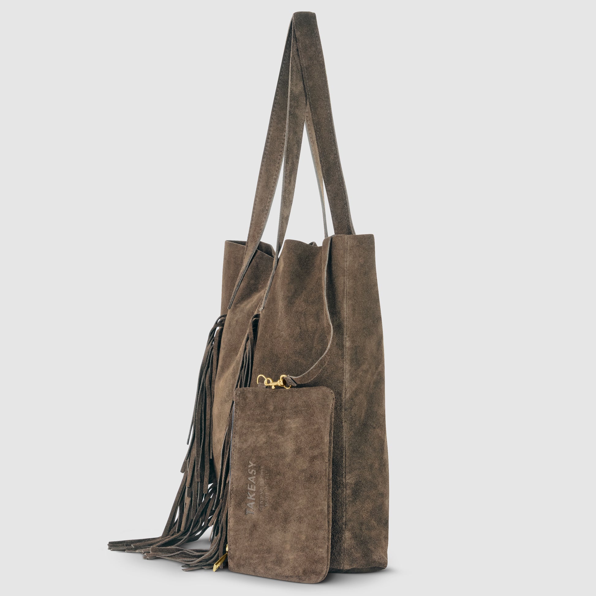 A brown suede handbag with long handles, decorative fringe on the side, and a matching zippered pouch attached. The pouch has TAKE IT EASY embossed on the front—perfect for a relaxed bohemian handbag style.