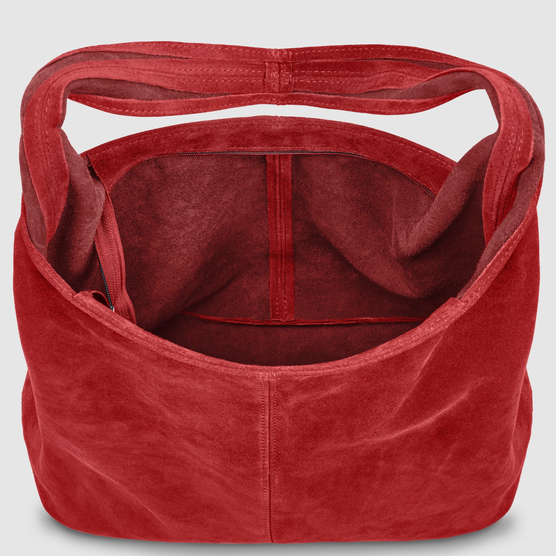 A top-down view of an open red Italian handcrafted bag with a wide handle, showing a spacious interior, a small side pocket, and visible seam details.