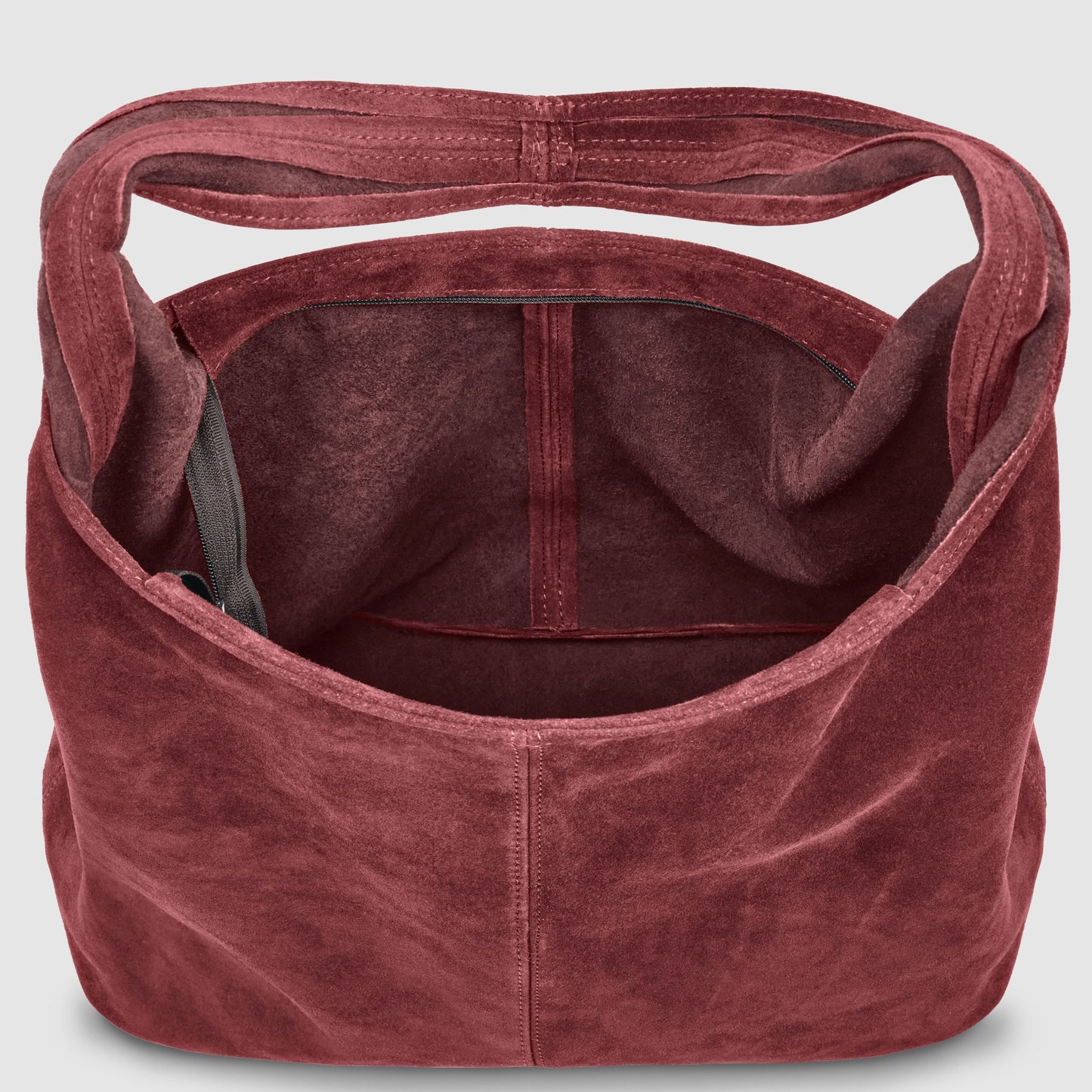 A top-down view of an Italian handcrafted bag in deep burgundy suede, featuring a single wide shoulder strap and a dark inner pocket—an effortlessly slouchy suede shoulder purse with ample room inside.