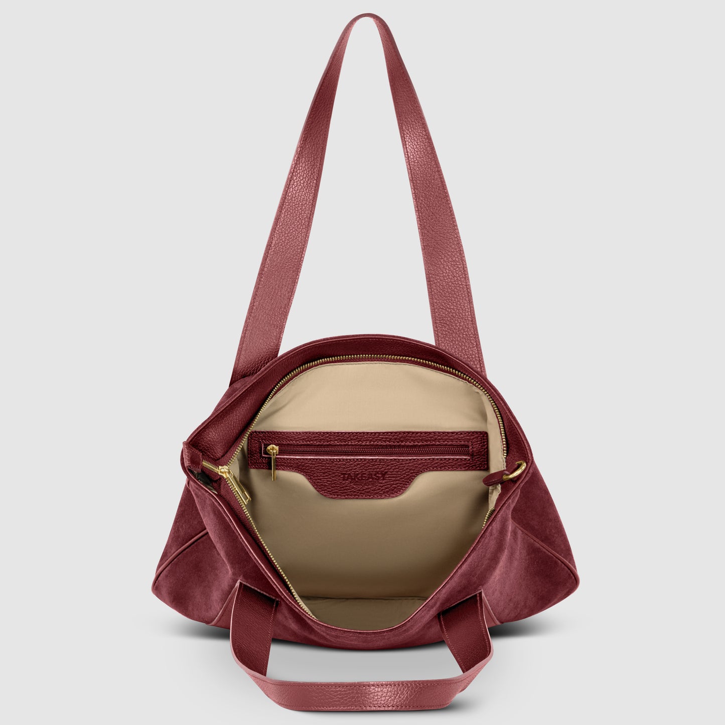 A burgundy Florentine leather bag with an open top reveals a beige interior, a zippered inner pocket, and two shoulder straps against a plain light gray background.