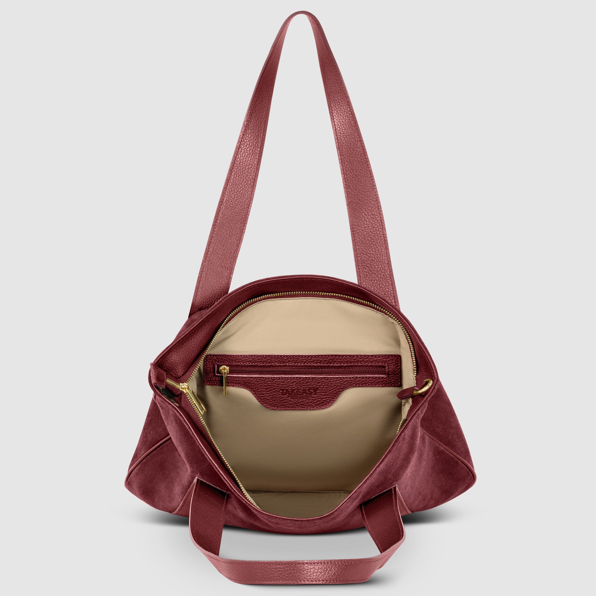 A burgundy Florentine leather bag with an open top reveals a beige interior, a zippered inner pocket, and two shoulder straps against a plain light gray background.