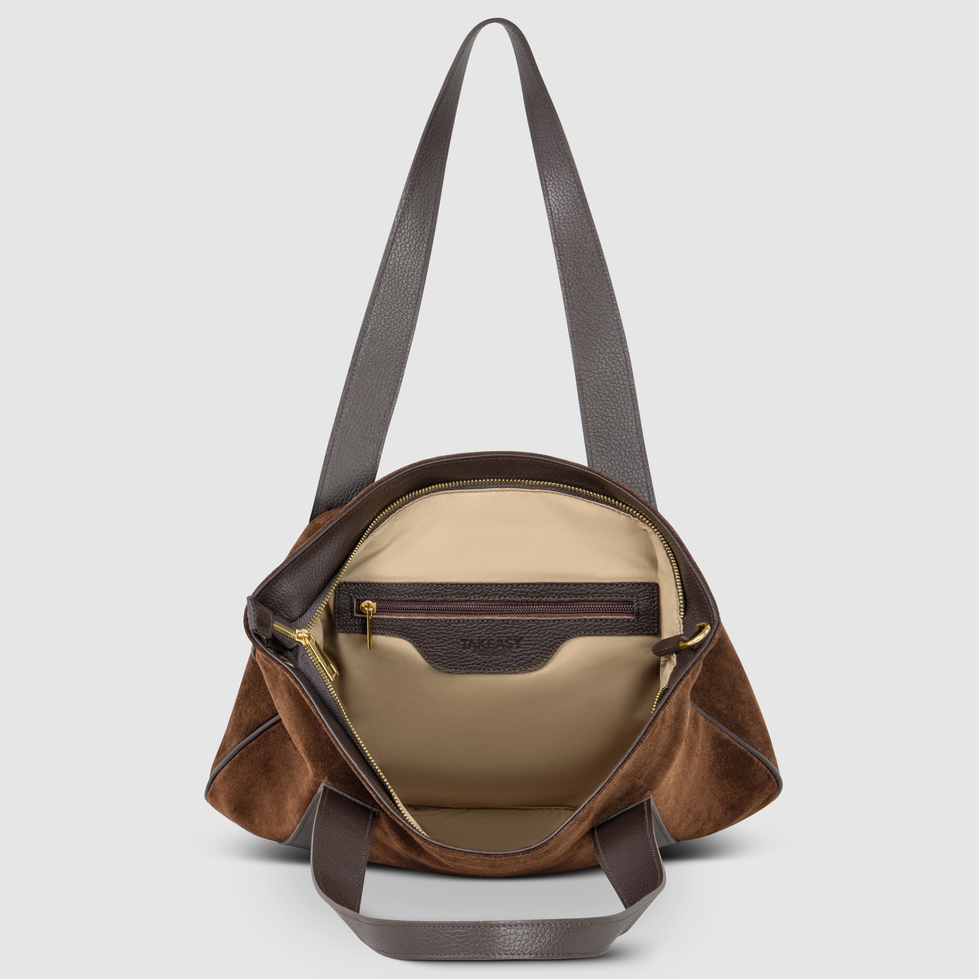 Open brown genuine suede bag with leather accents and dark brown handles. The beige interior features a zippered pocket and a leather DKNY label above it. This Italian style handbag is displayed against a plain light background.
