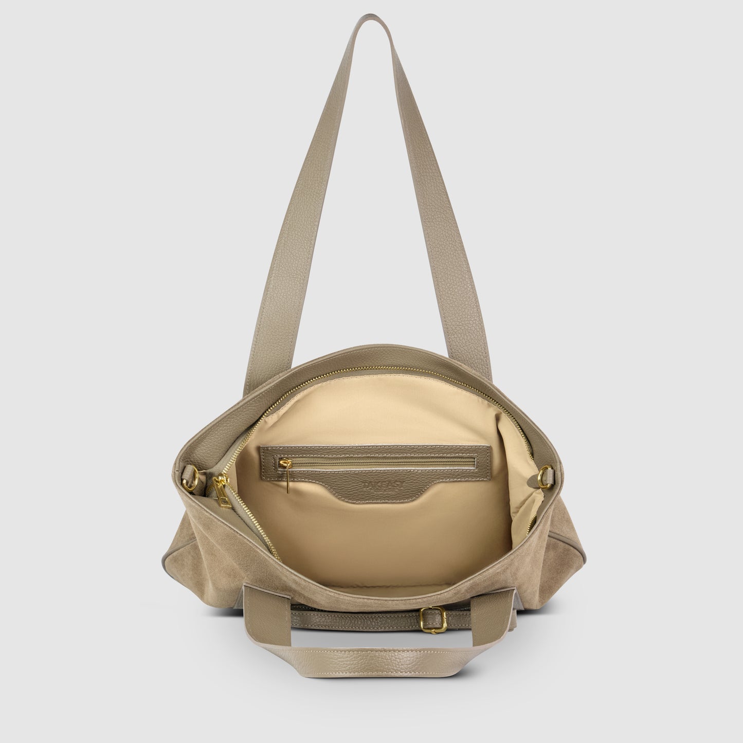 A taupe Italian leather bag with a wide strap is shown open, revealing a beige interior with a zippered pocket and gold zipper pulls. The outer texture blends suede and leather, reflecting classic Florentine leather traditions.