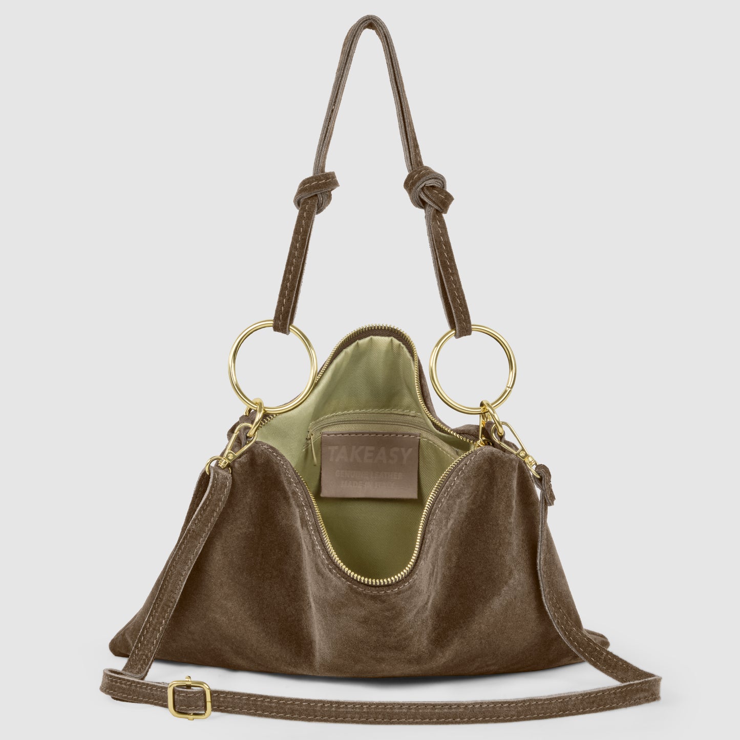 A brown suede leather purse with gold ring handles, tan adjustable shoulder strap, and green interior lining. This Italian handbag is open, revealing a label that reads TAKEASY inside.