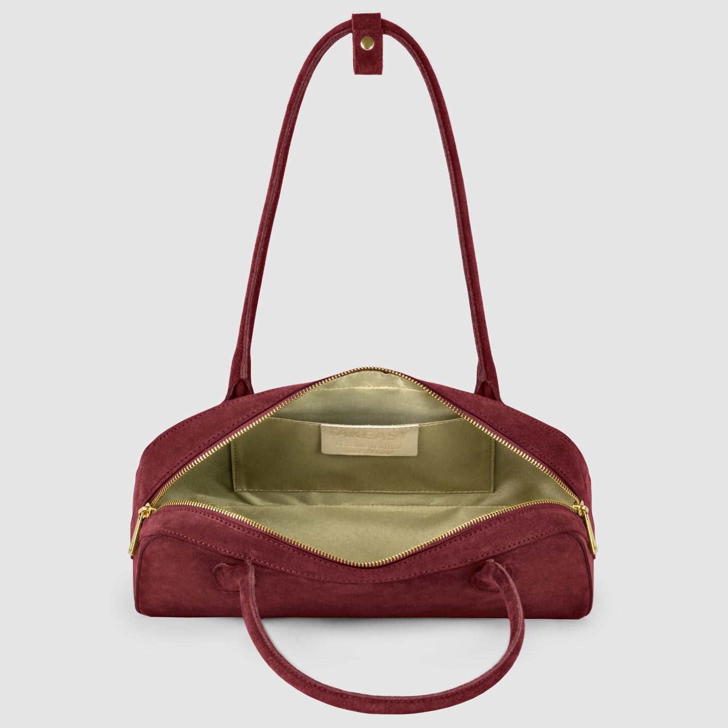 A maroon Italian suede bag with gold zippers, shown open to reveal a spacious, light green interior and an inner label. The bag has dual handles and a detachable shoulder strap.