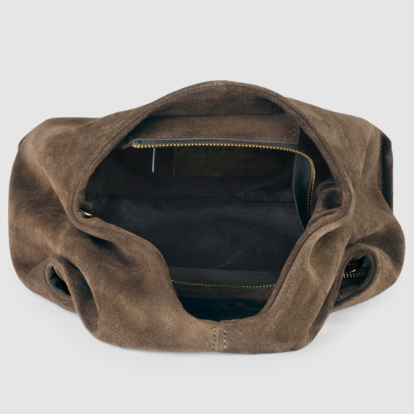 A brown handcrafted suede bag with its main compartment open, showing a spacious, dark-lined interior and a zippered pocket inside—an example of fine Florentine craftsmanship.