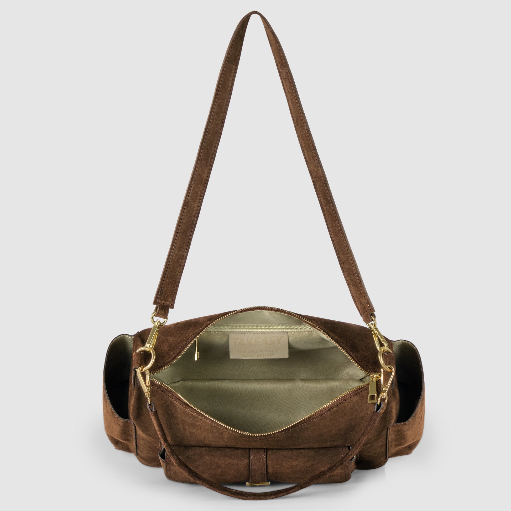 A brown genuine suede leather shoulder bag with gold zippers and hardware, shown open to reveal a spacious, light-colored interior. This handmade Italian handbag features a wide strap and side pockets, displayed against a plain gray background.