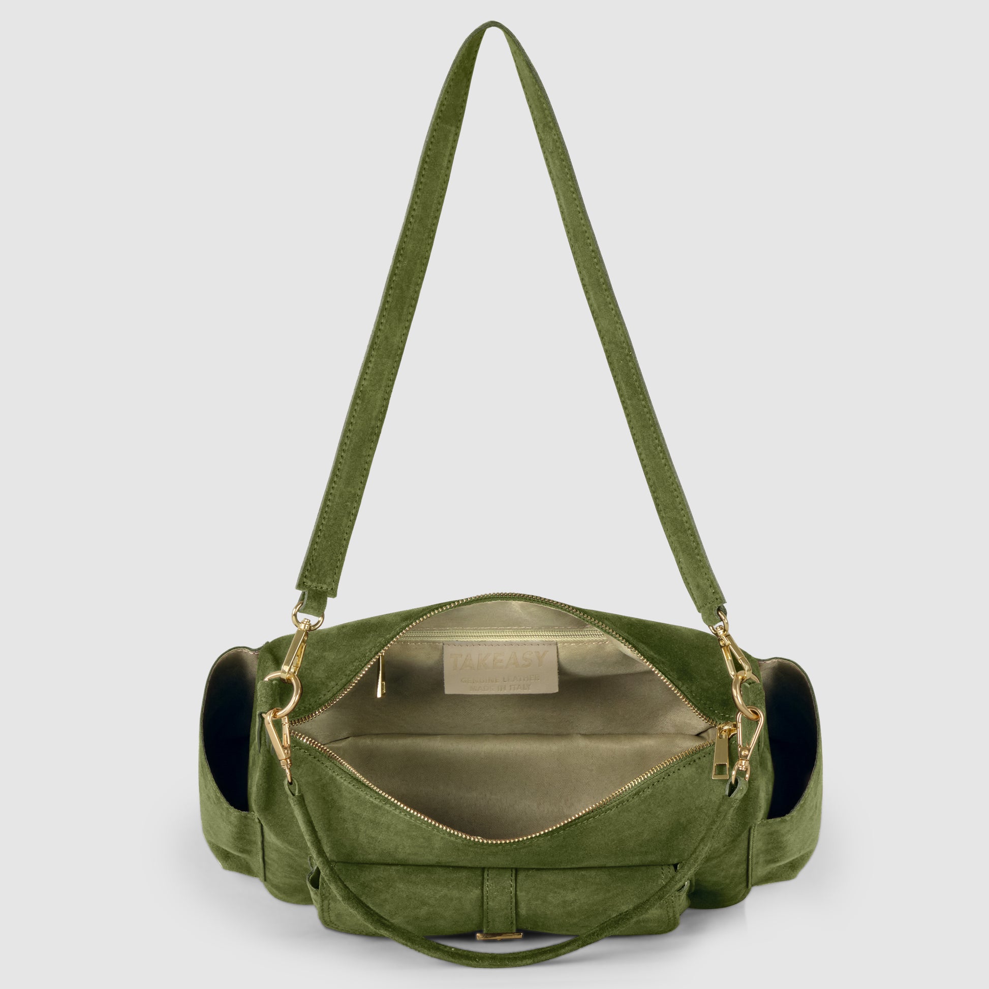 An open green suede leather bag with gold hardware reveals a spacious, light-colored interior and zippered pocket. Featuring a wide shoulder strap and side pockets, this piece highlights exquisite Florentine leatherworking against a light gray background.
