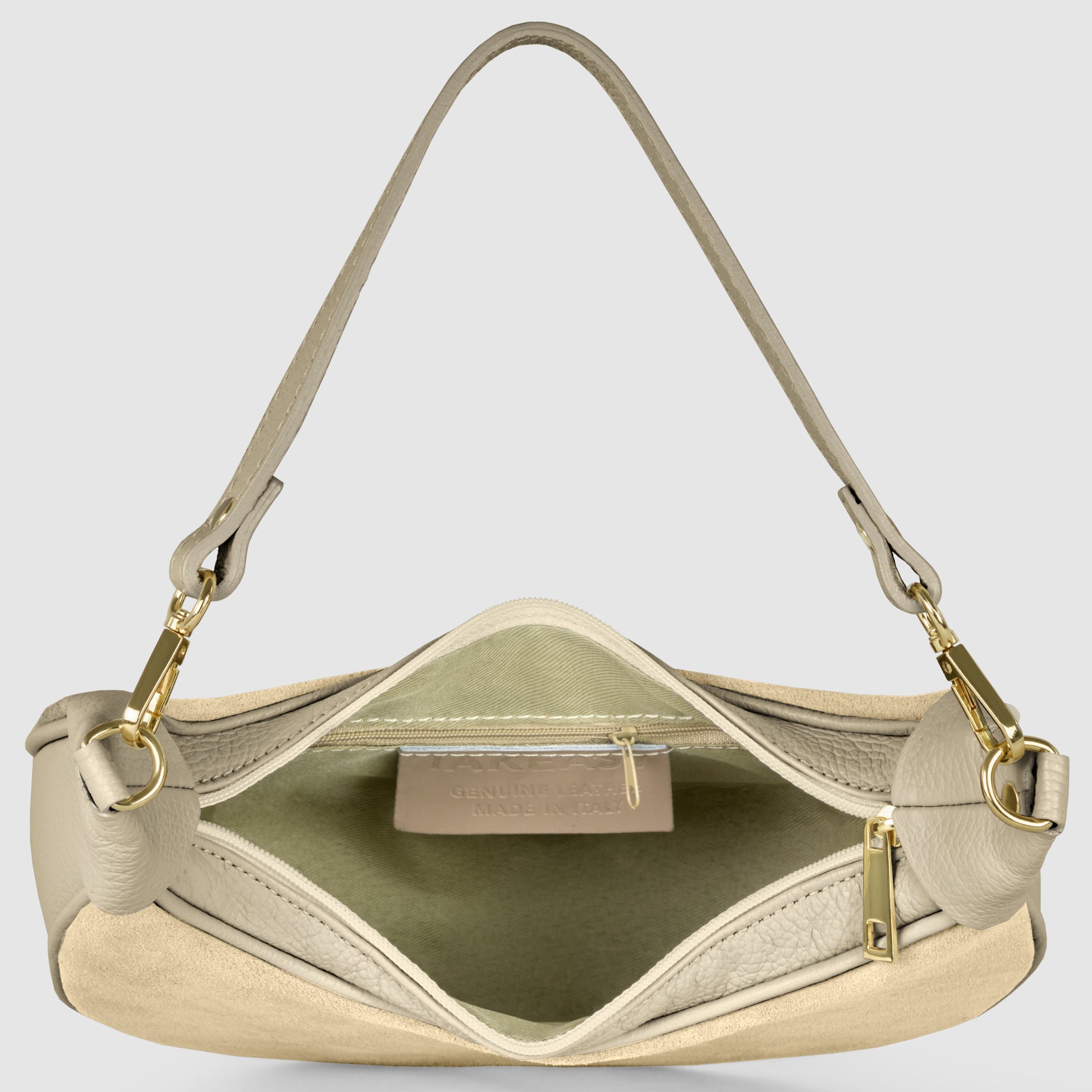 A beige crescent handbag crafted from Italian leather is shown open, revealing a fabric-lined interior with a zippered pocket and visible label. Gold hardware and a single shoulder strap attached with gold clasps complete the elegant design.