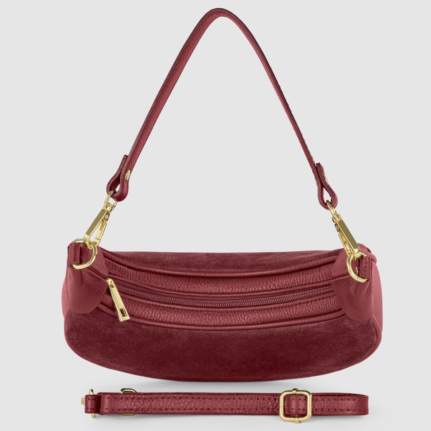 A maroon suede crescent handbag with gold hardware, a short shoulder strap, zipper closure, and an adjustable, detachable longer strap placed in front of the bag, all set against a light gray background.