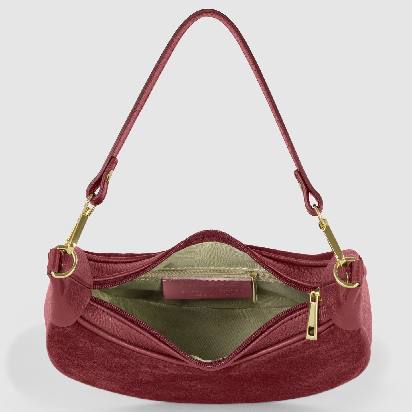 A maroon suede handbag with a gold zipper and hardware, this crescent handbag opens to reveal a light beige interior with a zippered pocket and a small rectangular patch inside.