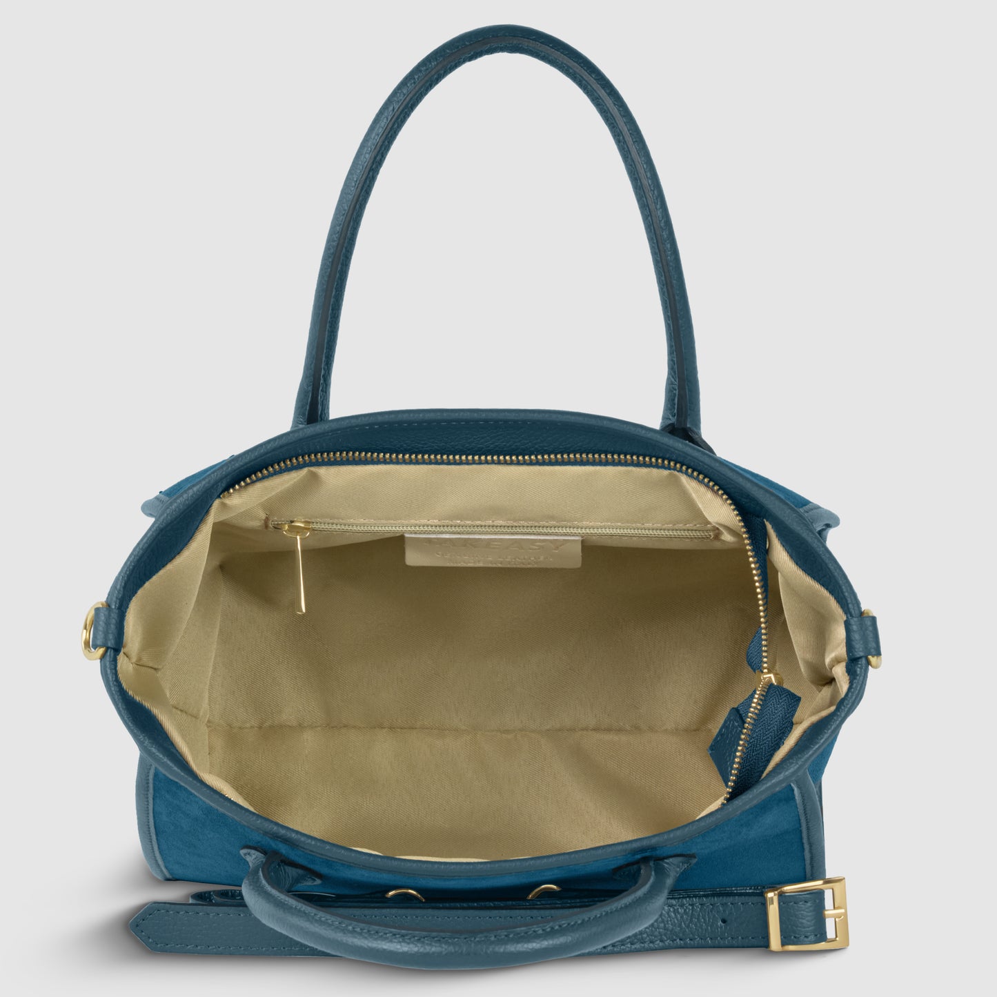 Blue suede leather handbag with gold hardware shown open from above, revealing a spacious beige interior, an inner zip pocket, and leather accents. Handcrafted in Florence, it features two handles and a detachable strap for everyday elegance.